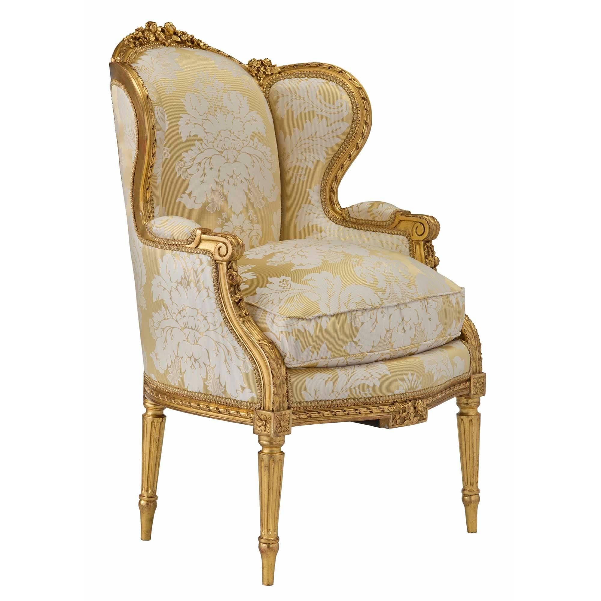 An exquisite pair of French 19th century Louis XVI style giltwood Bergères. Each chair is raised by four circular tapered fluted legs with rosette blocks at the front. A richly chased giltwood frieze has a twisted rope design with foliate front