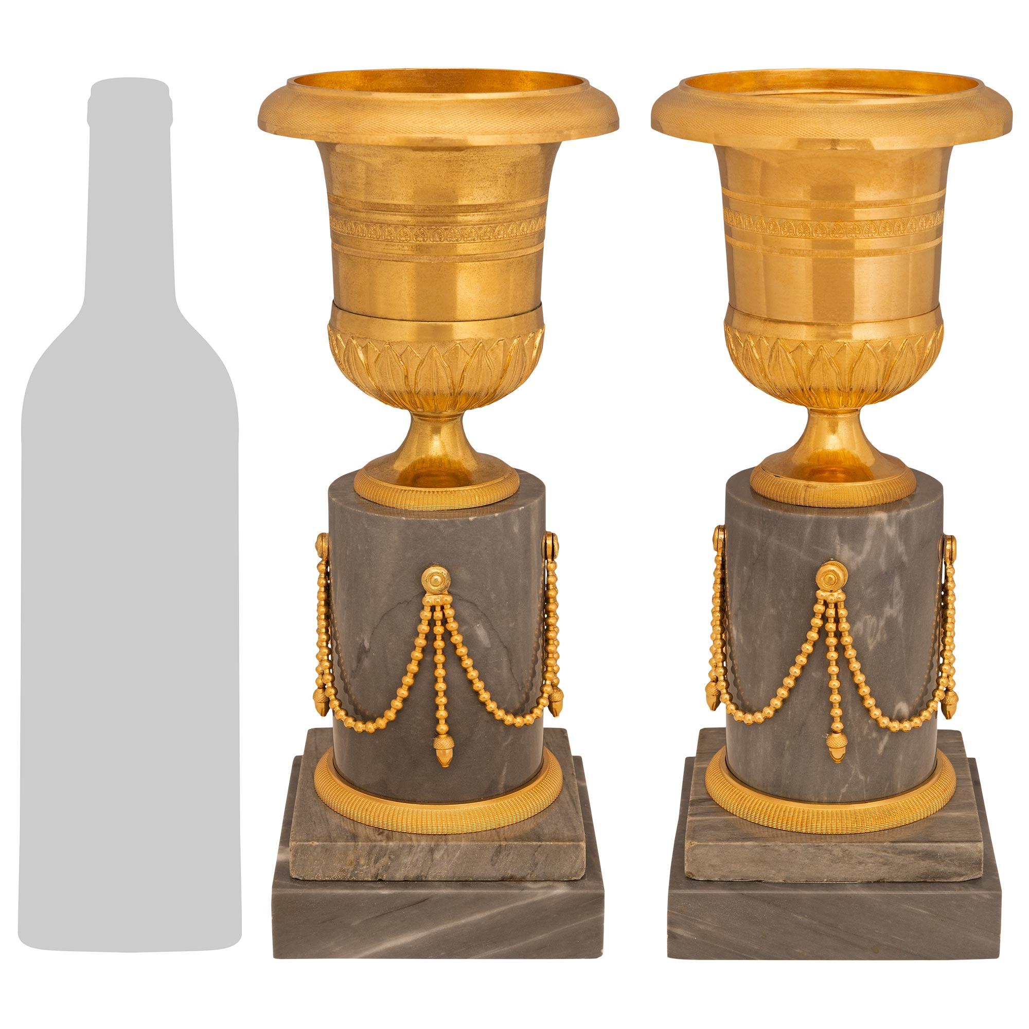 Paire d'urnes de grande qualité et décoratives en marbre et bronze doré de style Louis XVI du XIXe siècle. Chaque urne est surmontée d'une colonne circulaire en marbre, d'un socle carré et d'une bande de bronze doré à motif de treillis autour de la