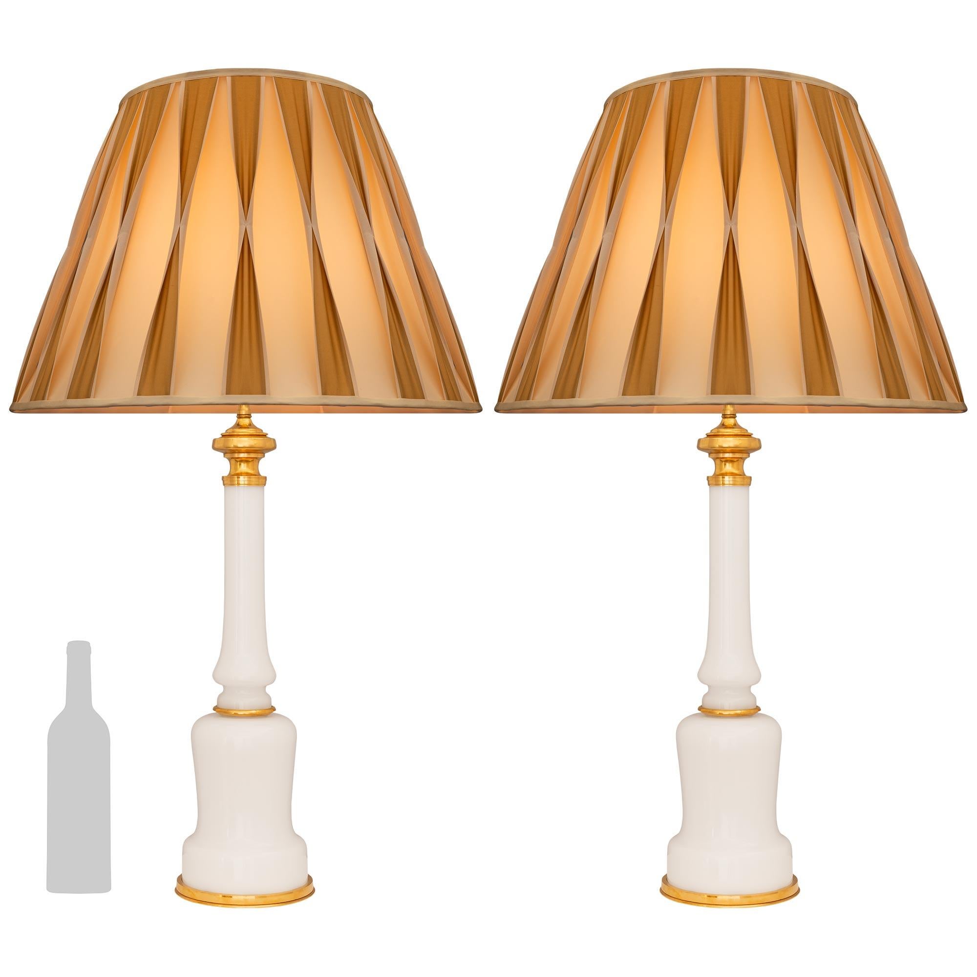 Une belle et très élégante paire de lampes en verre opalin et bronze doré de style Louis XVI du XIXe siècle. Chaque lampe est surmontée d'une fine base circulaire en bronze doré, située sous un support en opaline aux formes magnifiques et aux