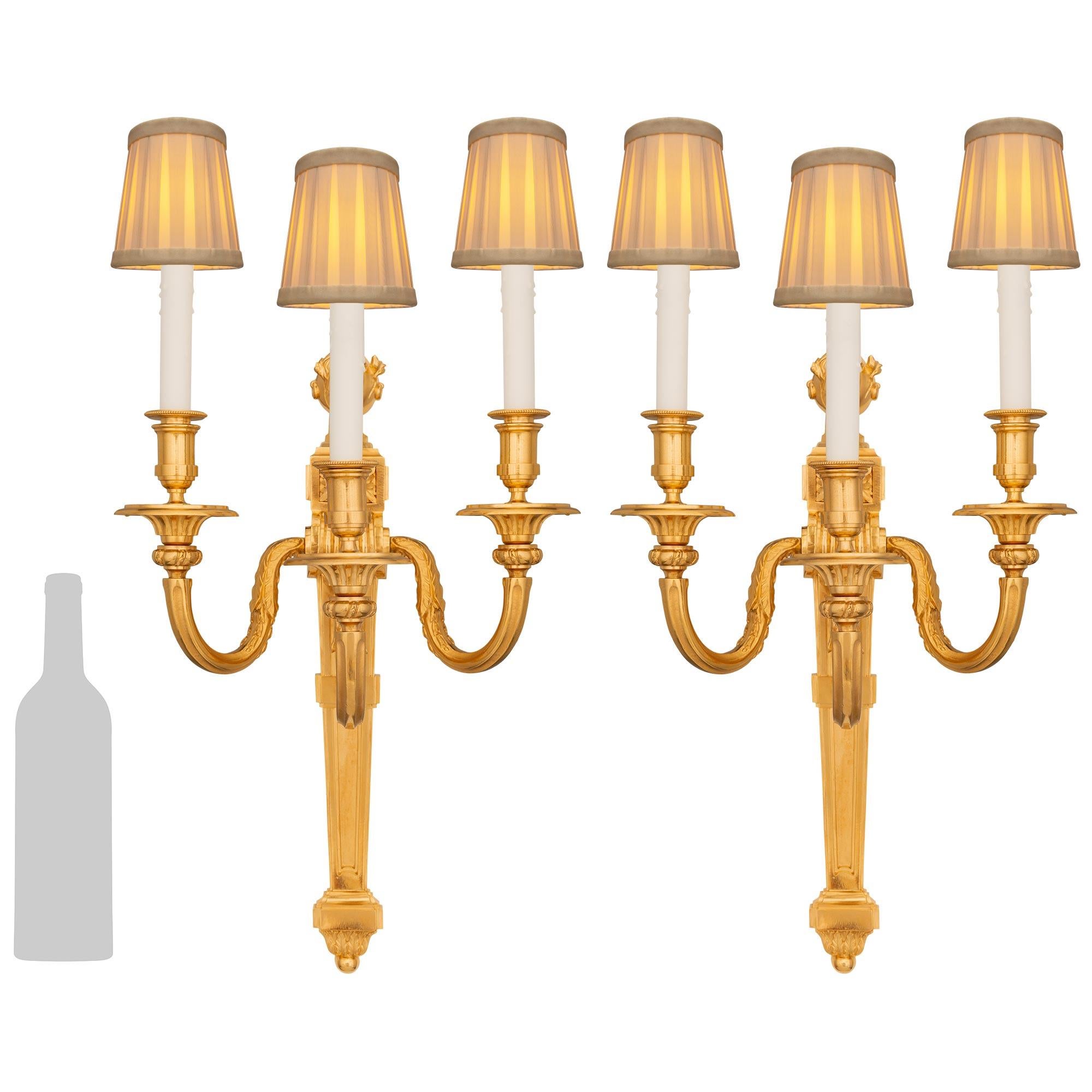 Pareja de apliques franceses de Ormolu del siglo XIX, estilo Luis XVI, de gran calidad. Cada bello candelabro está centrado por un remate inferior circular bajo decoraciones foliadas que salen del plinto de la columna superior. La placa posterior,