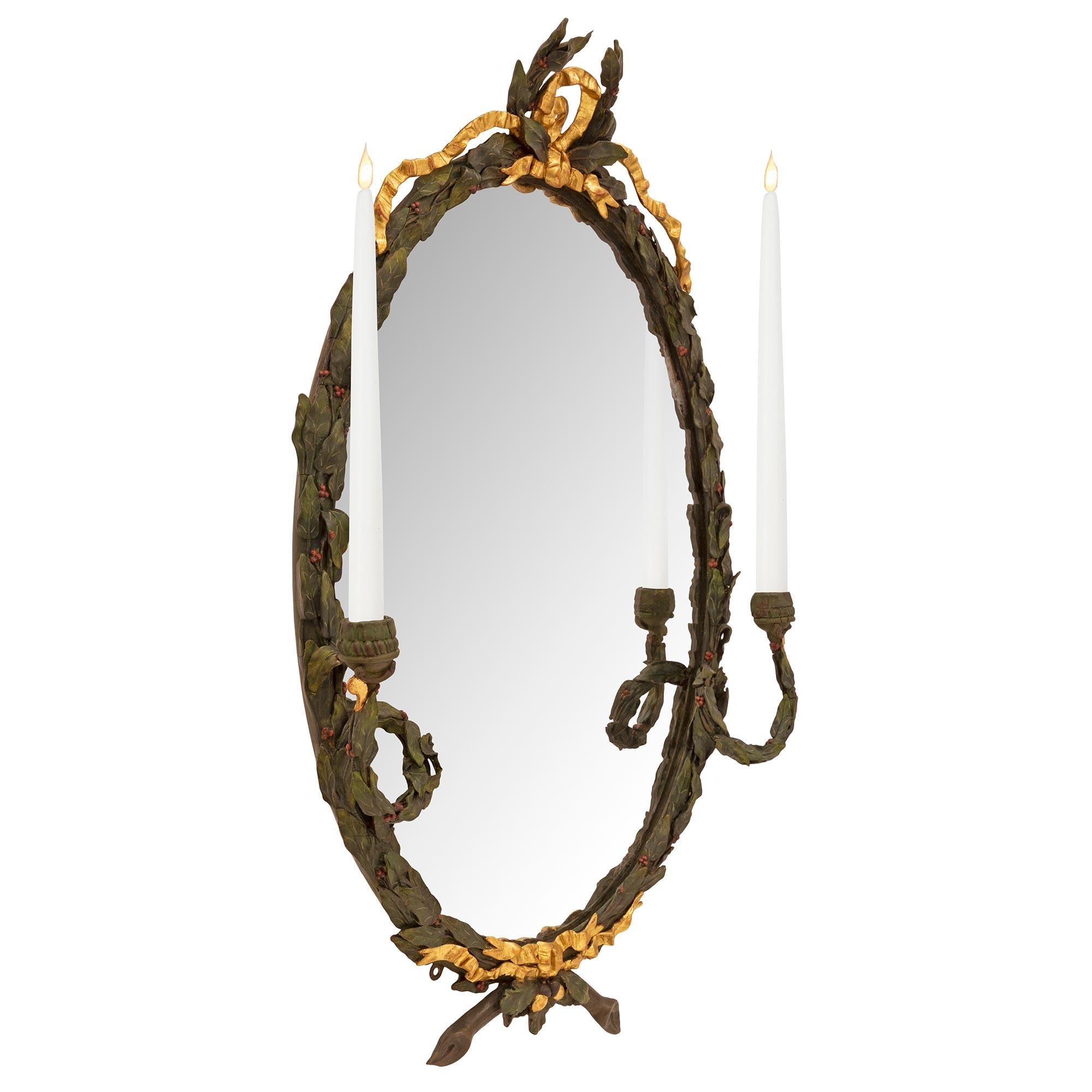 A beautiful and most decorative pair of French 19th century Louis XVI st. patinated wood and giltwood mirrors/sconces. Each mirror retains its original mirror plate set within a beautiful richly carved patinated forest green berried laurel frame