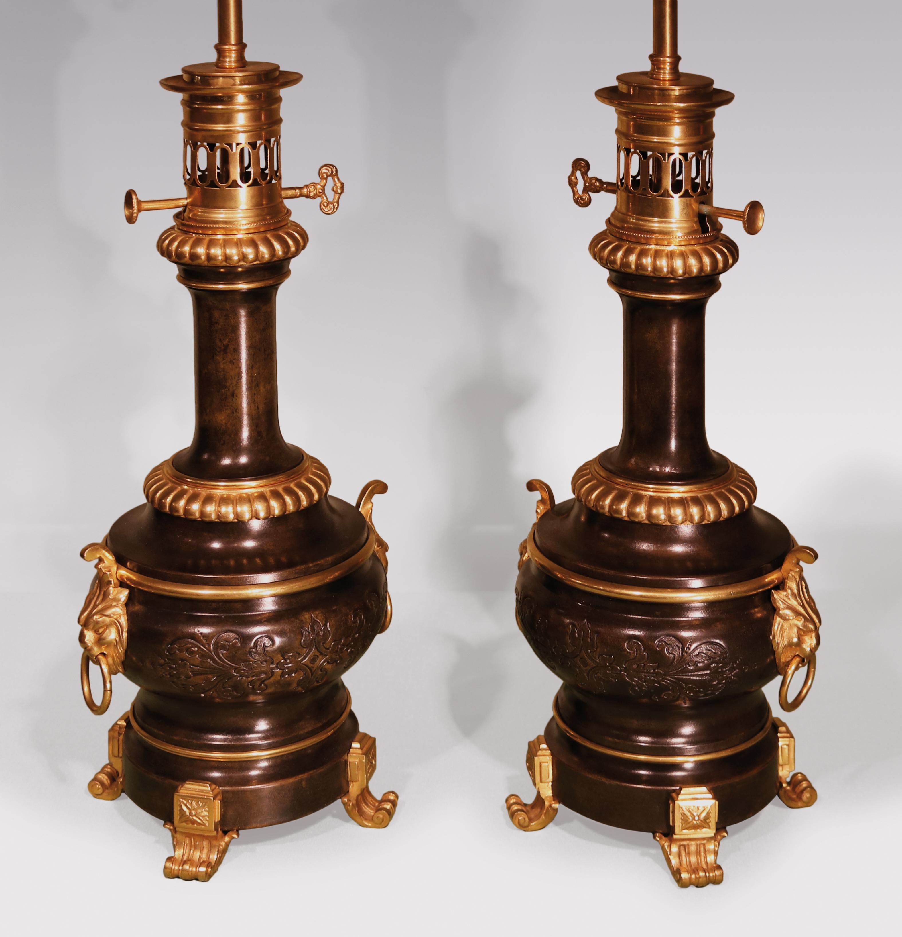 A pair of 19th century bronze & ormolu French Moderateur oil lamps in the form of bulbous vases, with embossed leaf decoration and satyr mask handles, supported on scrolled feet.

(Now converted to electricity).