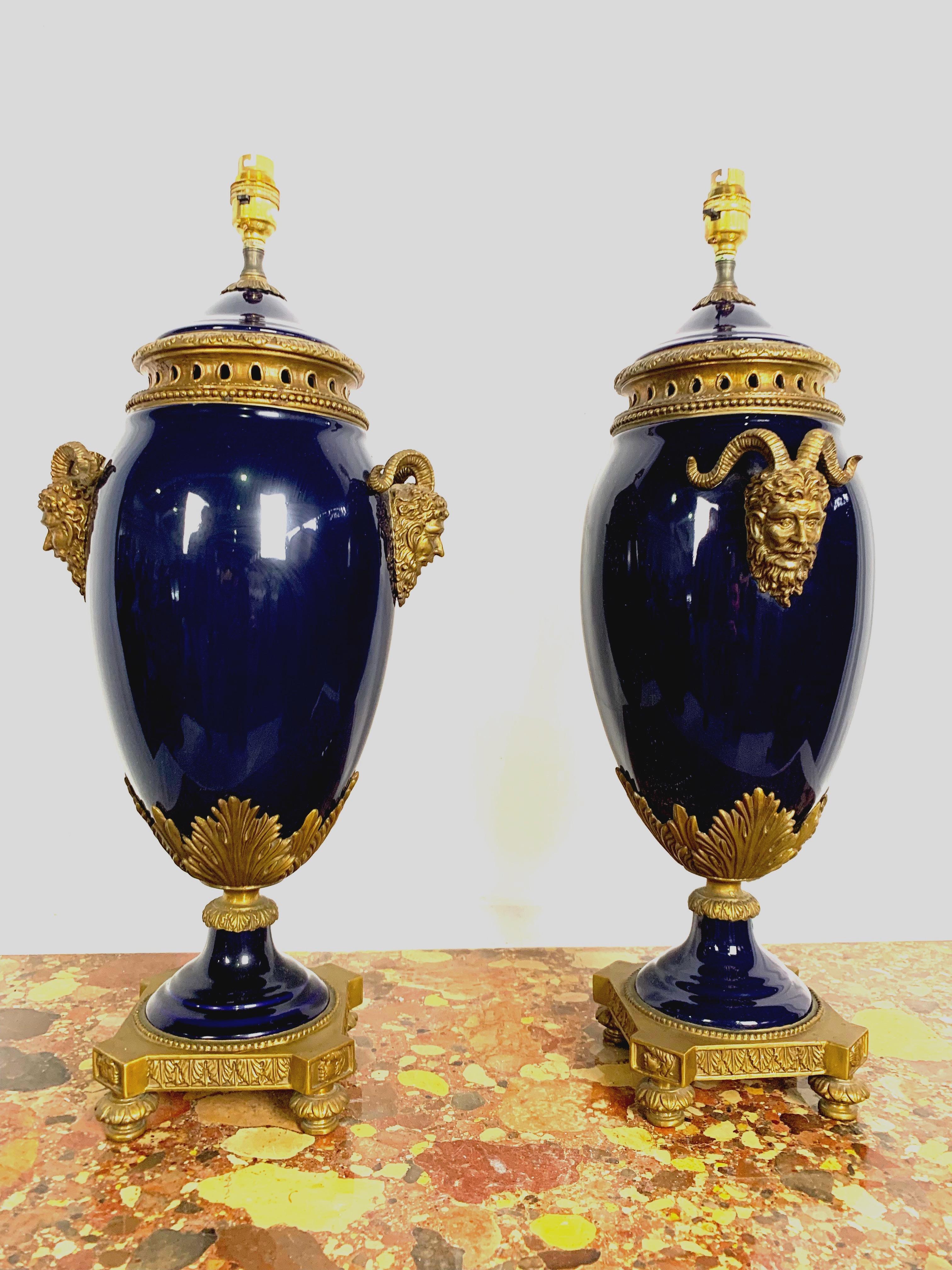 A very elegant pair of French 20th century Louis XVI. Cobalt blue Sèvres porcelain and ormolu lamps. Each lamp is raised on an ormolu base with beaded borders. The baluster shaped Sèvres porcelain body is decorated with lovely ormolu heads of Greek