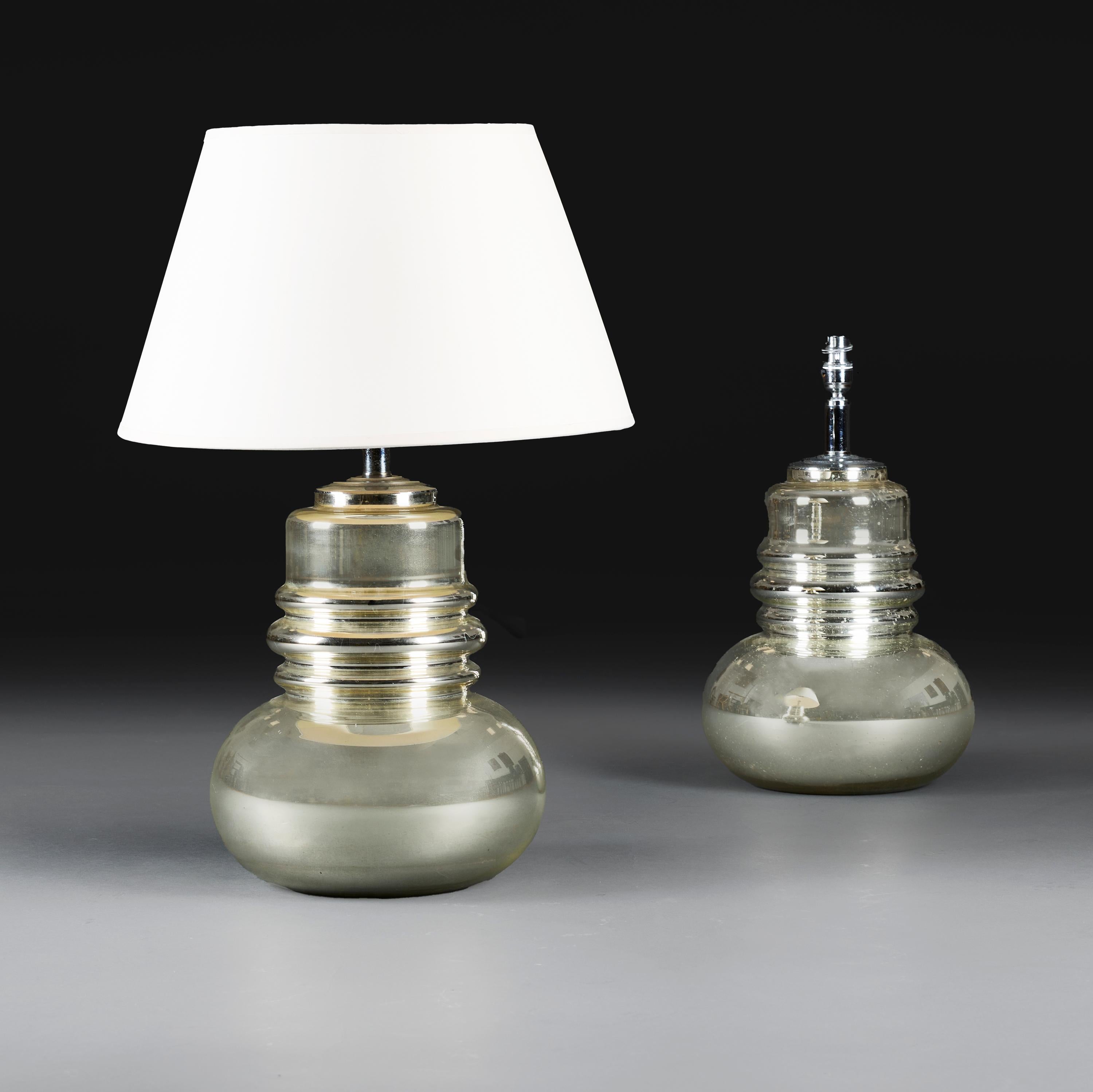 France, vers 1950.

Paire de lampes bulbeuses en verre au mercure, le corps trapu avec un col allongé décoré de bandes saillantes.  

Hauteur 34,00 centimètres.
Hauteur avec abat-jour 59.00 centimètres.
Diamètre 26.00 centimètres.

Veuillez noter