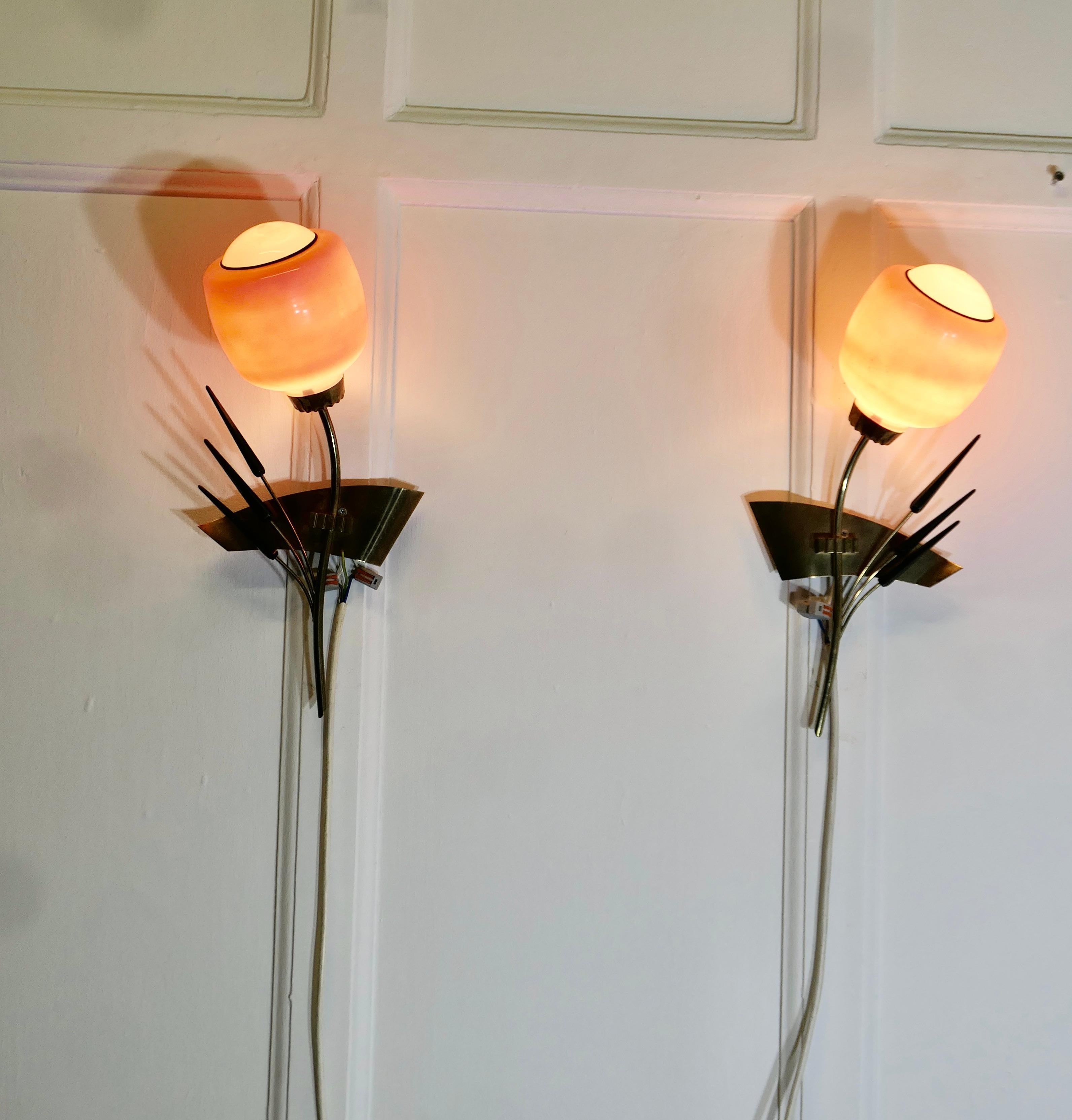 Coppia di lampade da parete in ottone retrò anni '50 a forma di covone di grano, 

Una coppia di luci molto elegante, completa di paralumi in vetro rosa 
Tutti funzionanti, dovranno essere collegati a una presa di corrente. 
Le luci sono alte 15