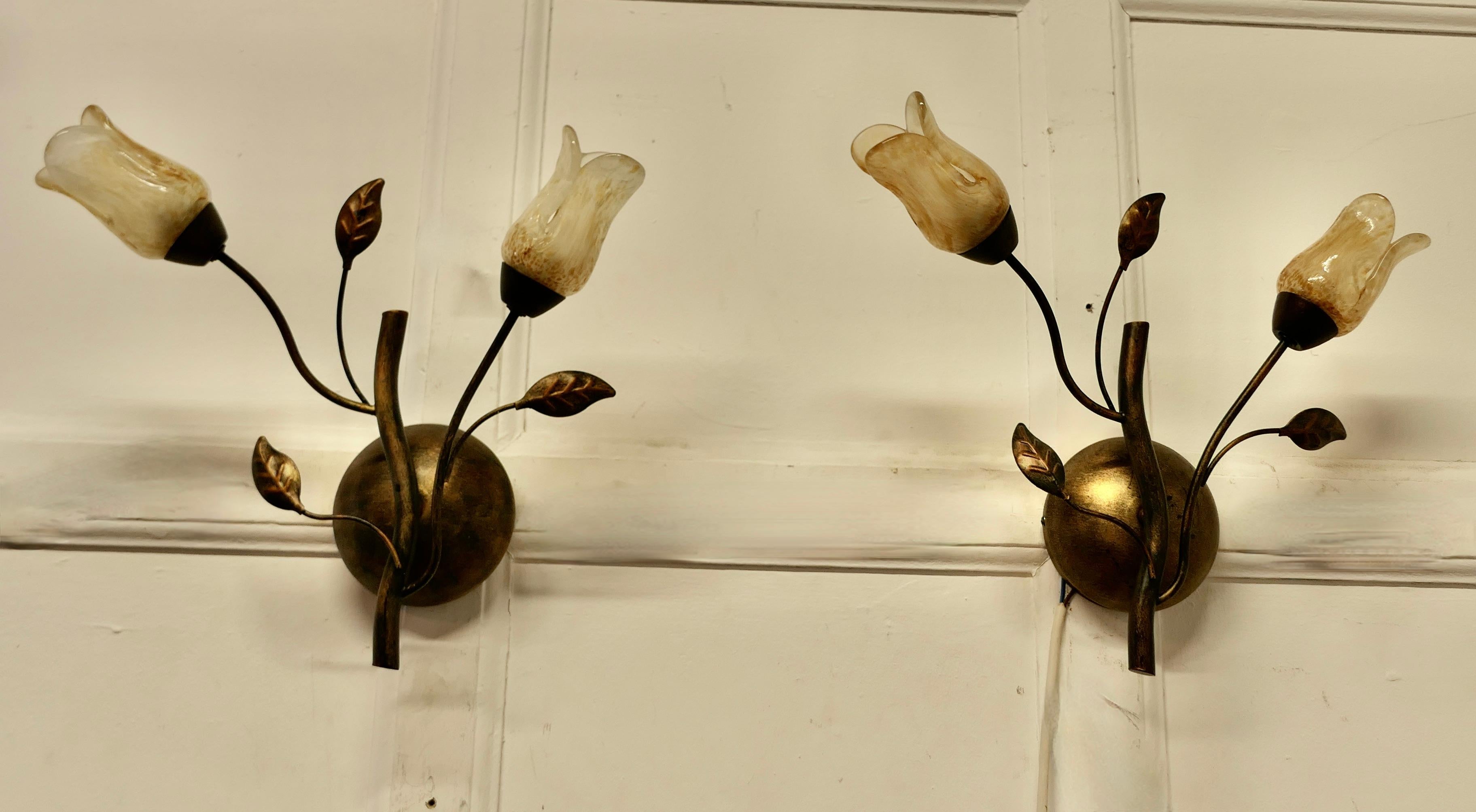 Pareja de apliques art déco franceses de vidrio ámbar y toleware dorado

Son un par de apliques muy bonitos, cada uno tiene 2 apliques de toleware con pantallas de cristal opalescente tintado de ámbar en forma de tulipán  
Las luces funcionan y