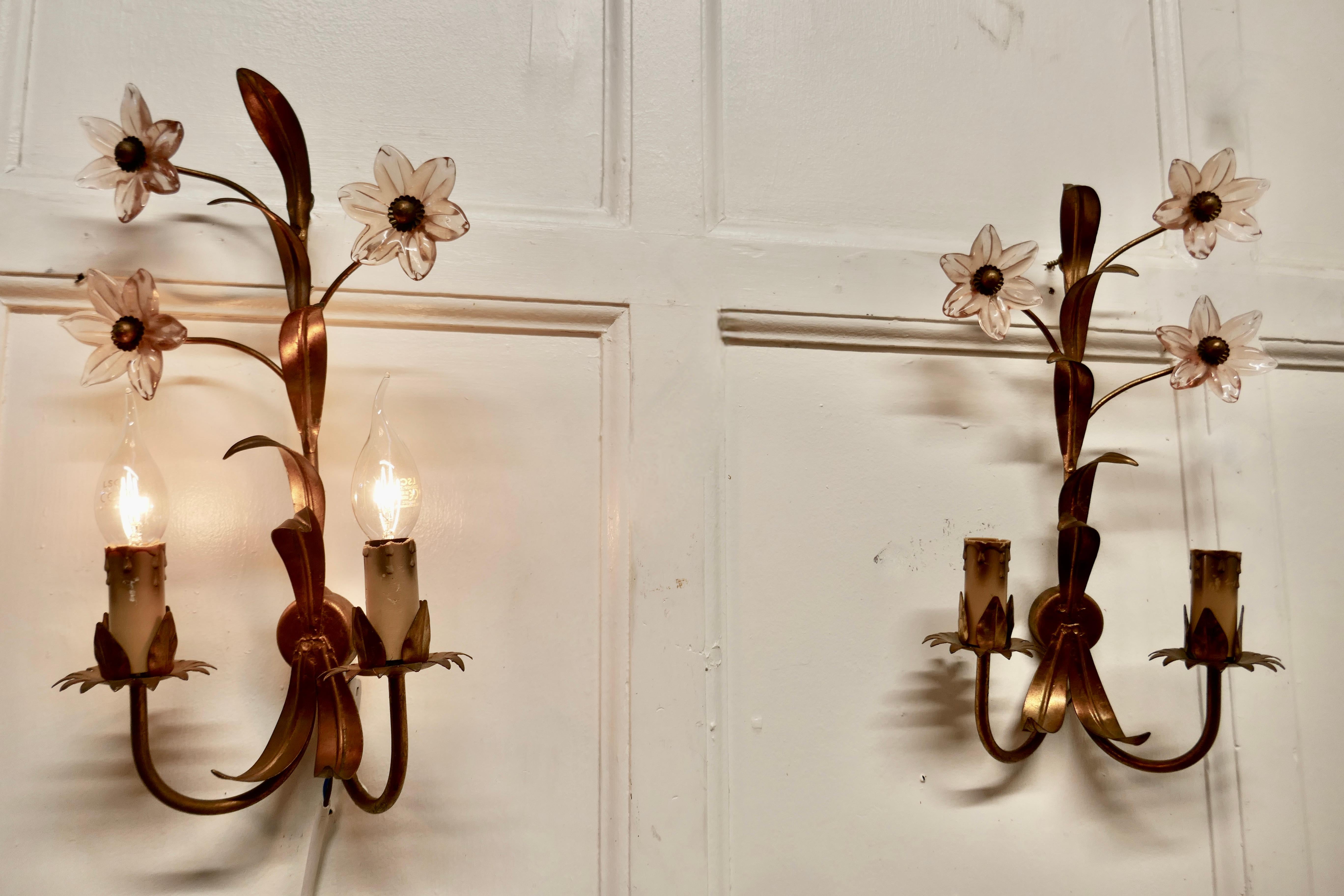 A Pair of French Art Deco Pink Glass and Toleware Gilded Wall Lights

These are a very pretty pair of wall lights, they each have 2 toleware sconces and curled gilt leaves which are decorated with delicate pink glass daisies 
The lights are