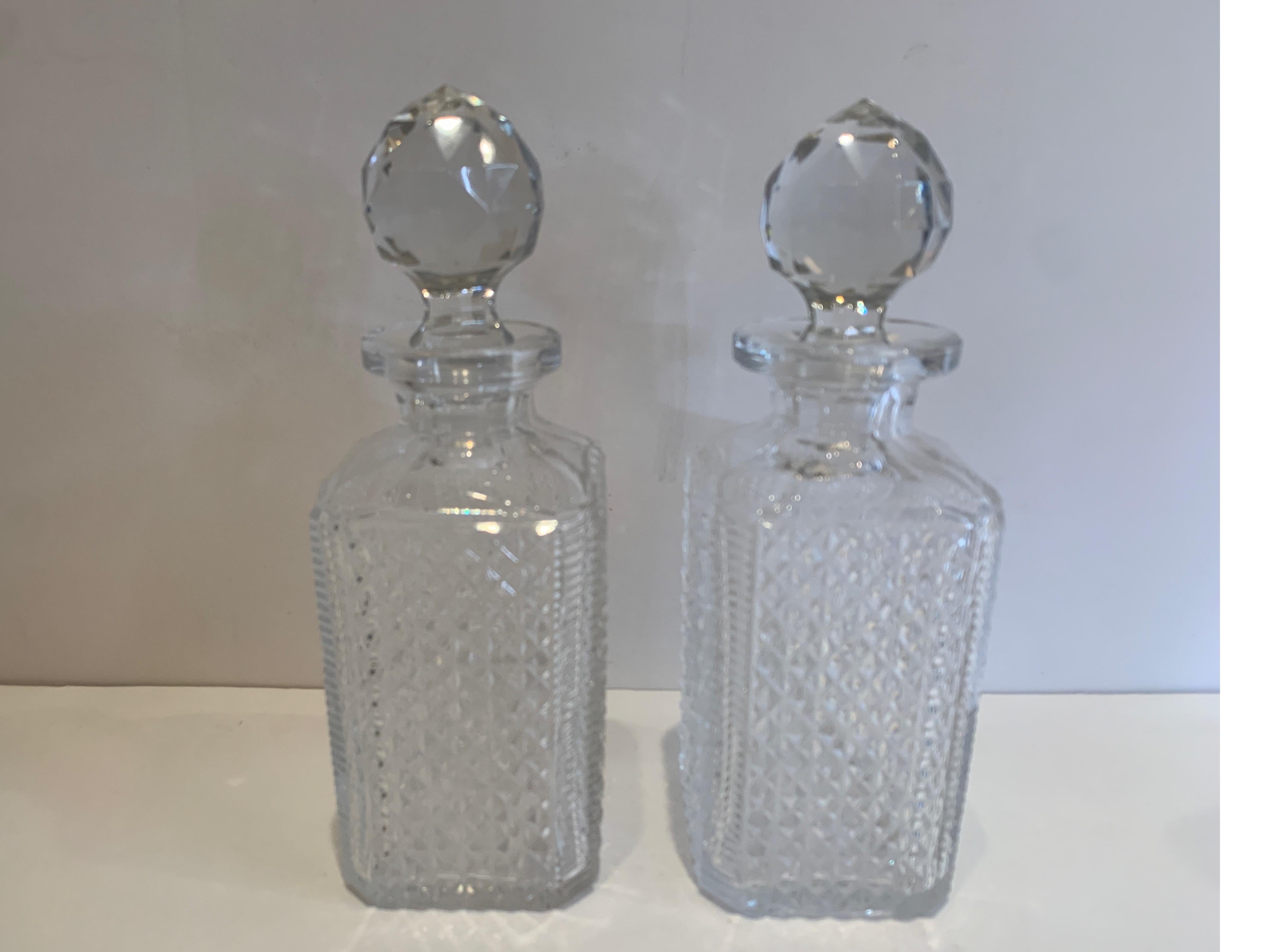 A beautifully cut pair of Baccarat whisky/scotch decanters with faceted stoppers. An original pair, each one handcut and polished on a cutters wheel, France, early 20th century.