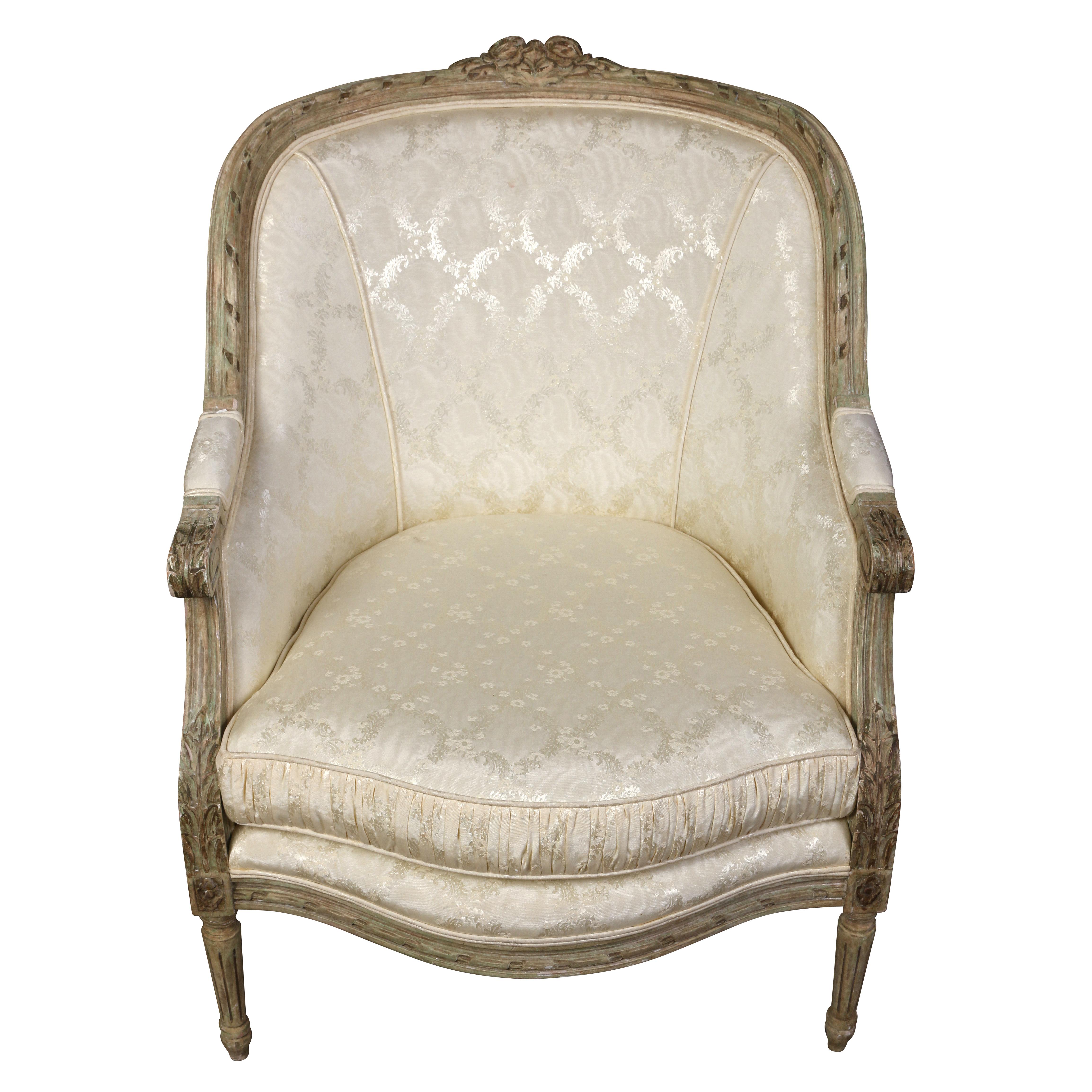 A pair of Louis XVI style painted bergères with a tight, rounded back and a loose seat cushion. Typical of the Louis XVI style, the chairs feature lovely carved details on the top and on apron, and fluted, tapered legs.