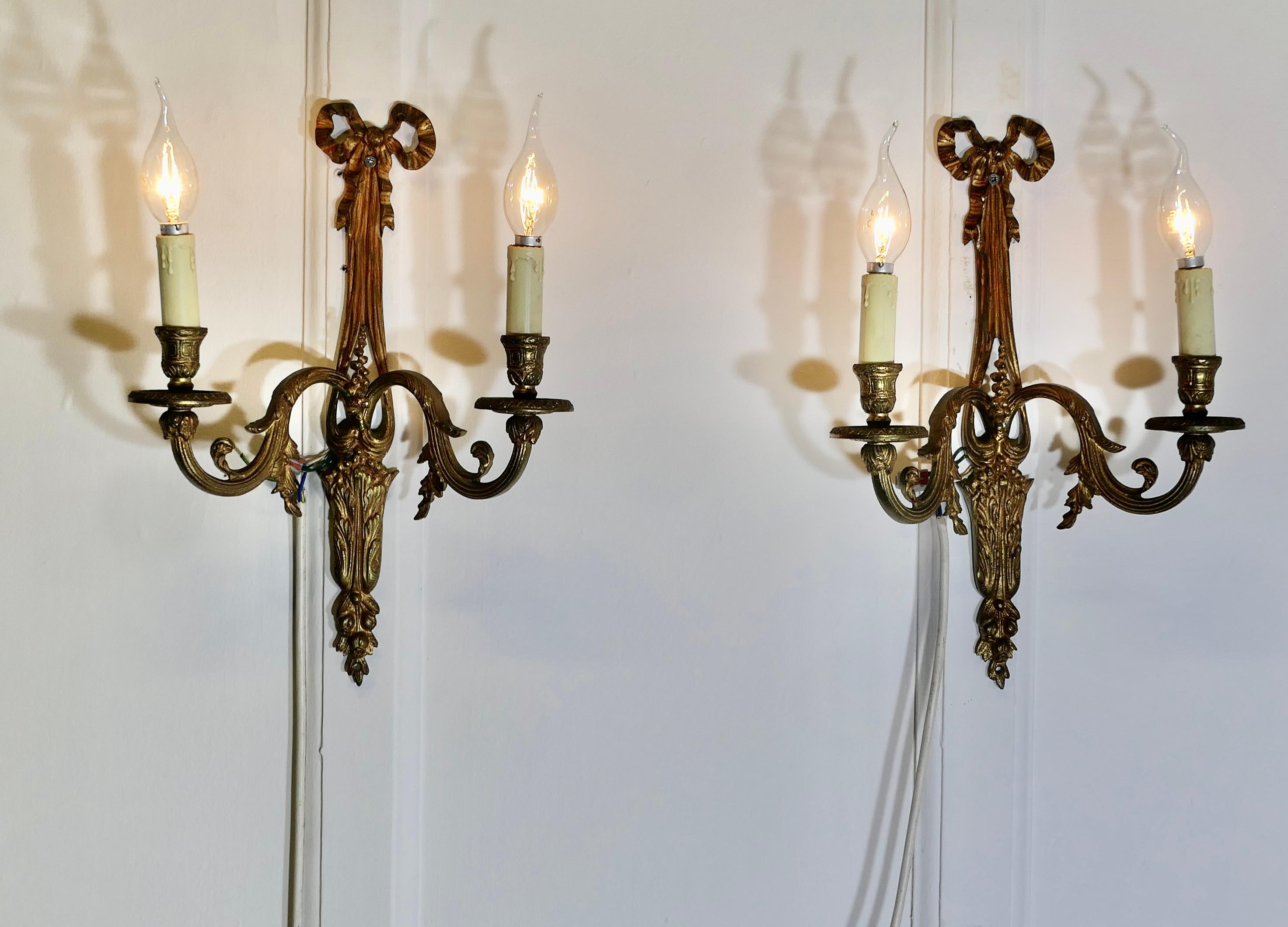 Pareja de apliques gemelos de latón francés  


Este es un par de luces muy atractivas cada una tiene 2 apliques y están decoradas con cintas y lazos

Las luces están en buen estado vintage y funcionan, habrá que conectarlas a una toma
