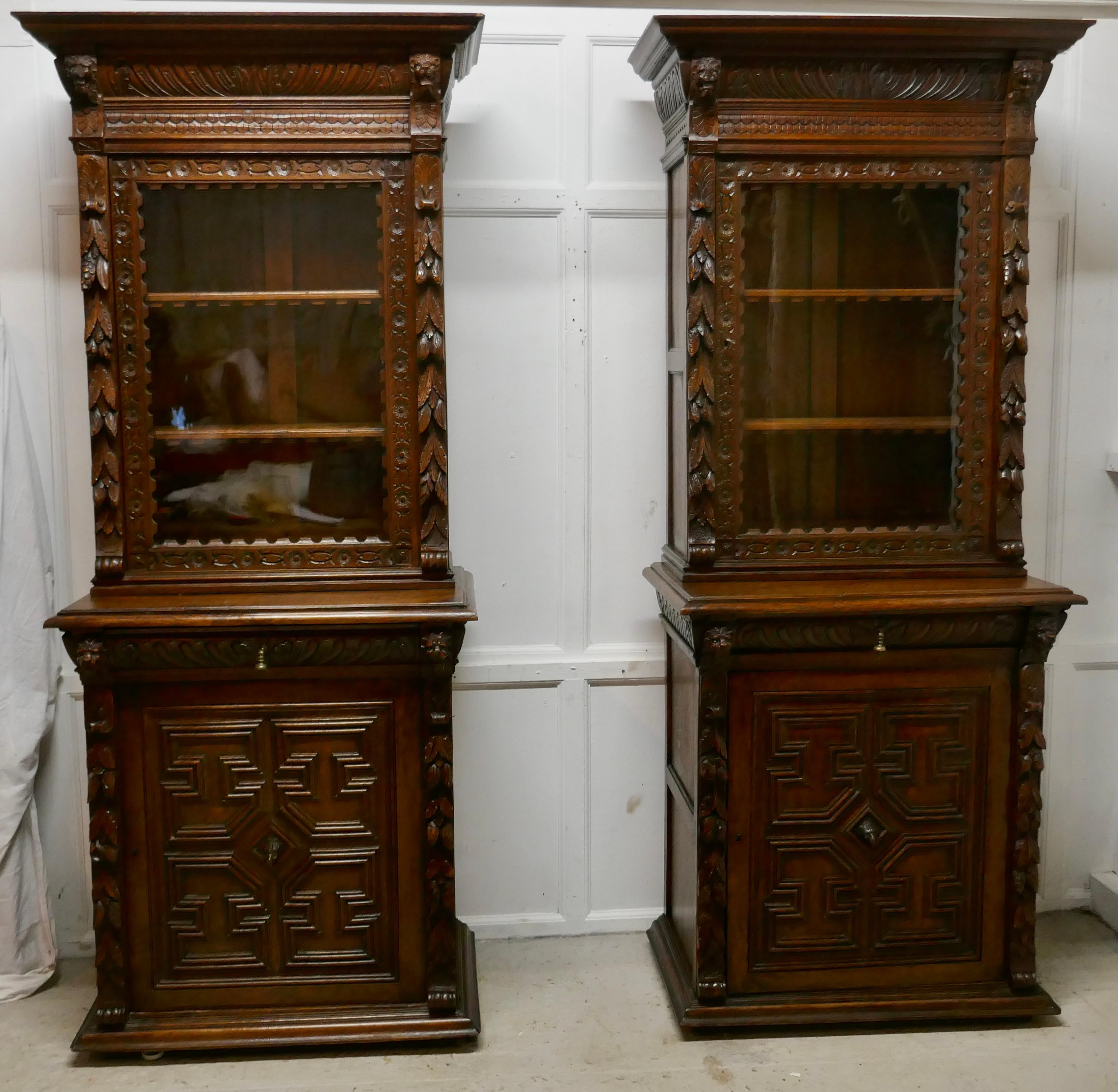 A Pair of French Carved Gothic Oak Bookcases

The upper section of the Bookcases have a glazed door enclosing 2 adjustable book shelves, these have an attractive carved front edge. 
The Tops have a large carved cornice and there is carving on the