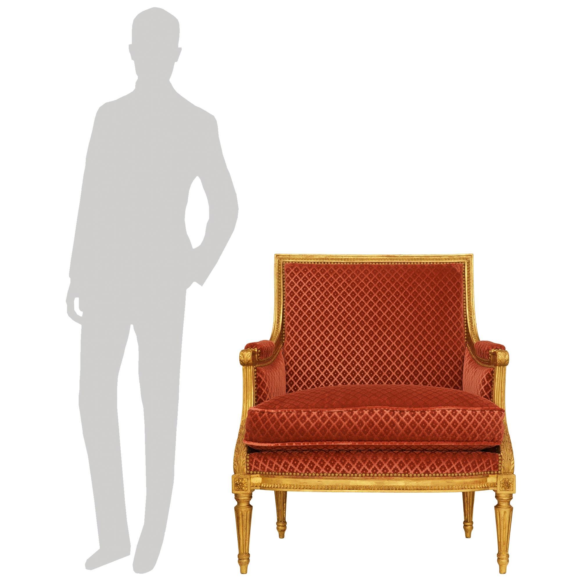 Magnifique et très élégante paire de fauteuils en bois doré de style Louis XVI du début du XIXe siècle. Cette superbe paire de fauteuils bergères repose sur des pieds circulaires fuselés et cannelés, avec de charmants supports inférieurs en forme de