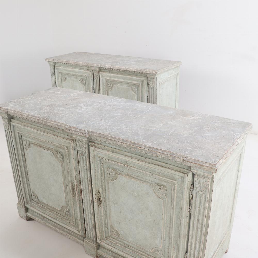 Each with a faux marble molded top overhanging a case with over two cupboard doors separated and flanked by 3 fluted columns with Corinthian capitals, above a stepped apron resting on square molded block feet. 

This pair would be wonderful in a