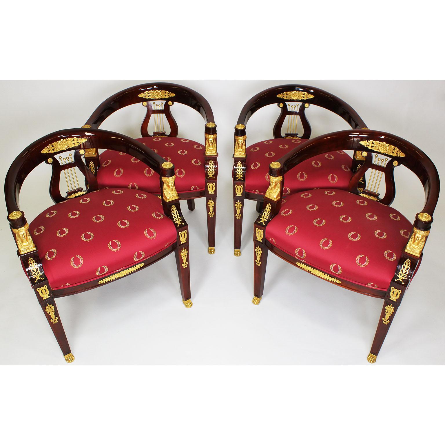 Ein Paar französische Sessel aus Mahagoni und vergoldeter Bronze in Form eines Hufeisens (Reproduktionen) im Empire-Stil. Die gewölbten Rückenrahmen sind mit einem Harfenmotiv unter einem Lorbeerschild zentriert, die Armlehnen jeweils flankiert von