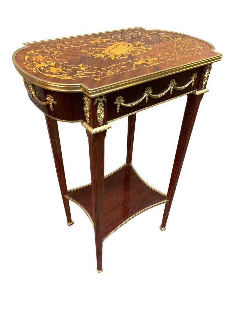 A stunning pair of French Empire side tables, 20th century. Ormolu fixtures are original and include table top protectors, and beautiful ribbon stretchers. Elegant pair ready to take centre stage as part of any high end interior.