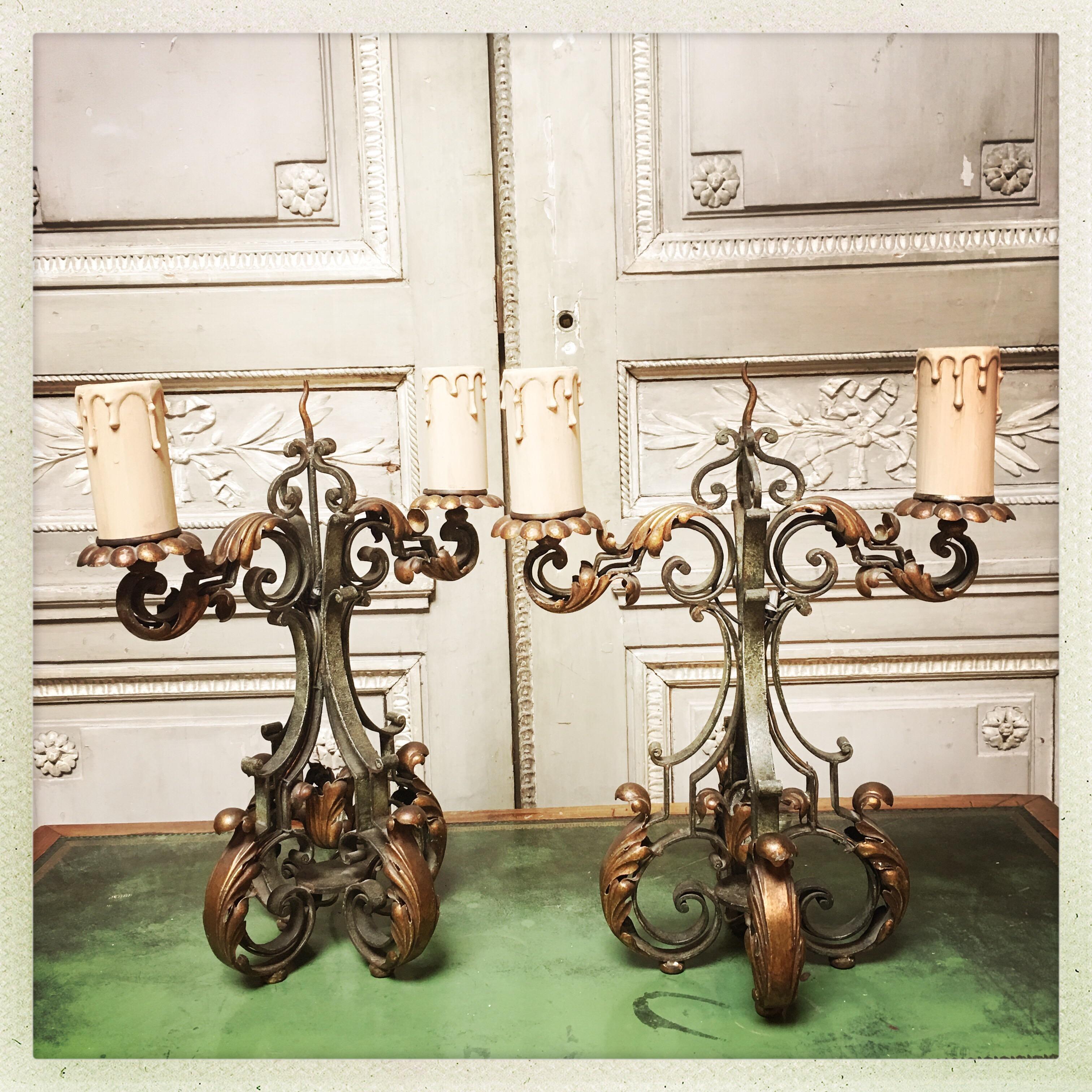 A pair of French forged iron two-arm candelabra with a painted and parcel gilded finish.