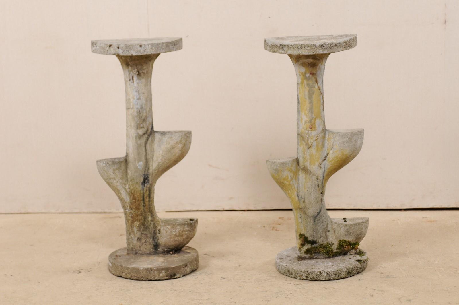 A French pair of garden foliage inspired, tiered sculptural shelves from the mid-20th century. This vintage pair of cast-stone garden or patio decorations from France each features a rounded base which supports a plant shaped sculpture, topped with