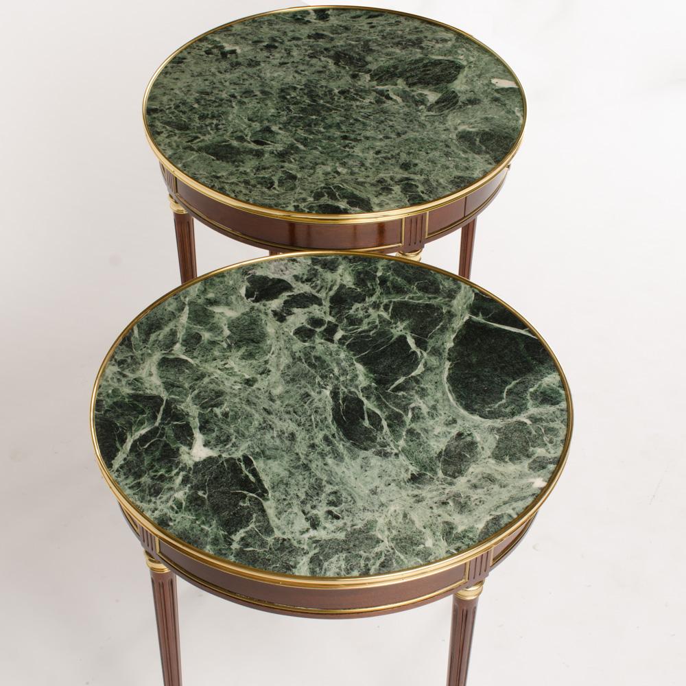 A pair of French mahogany and brass gueridon tables, Directoire style, circa 1940. Beautiful green marble top banded by bronze and supported by four fluted and tapered legs terminating with casters. Unusual and desirable large size.