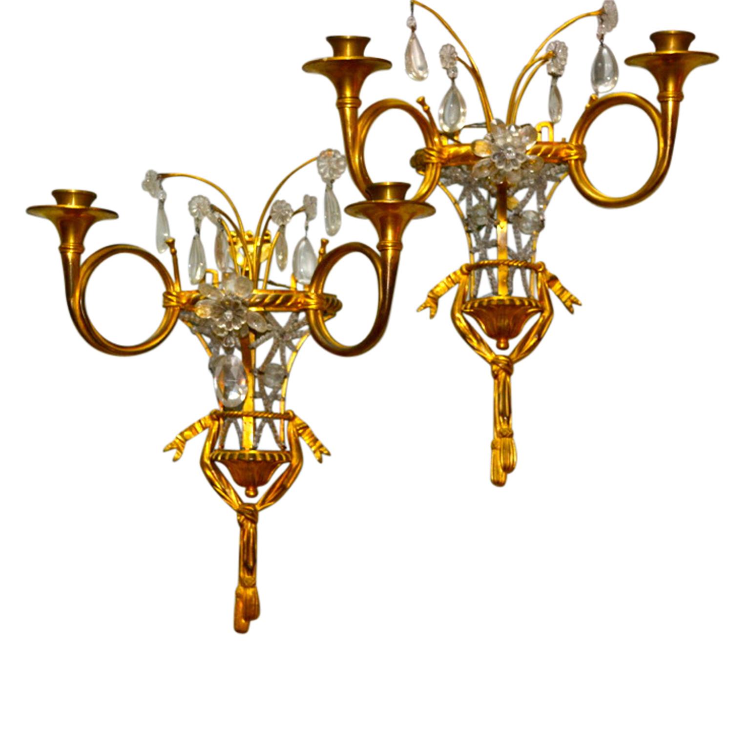 A pair of unusual shaped gilt metal and crystal wall sconces. The half urn shaped body is open and is criss crossed with beaded crystals; the bottom of the 'vase' has gilt bronze decoration in the form of swags and ribbons. From the top of the vase