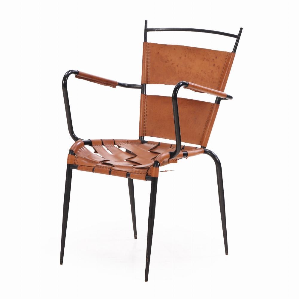 The minimalist blackened iron frames feature clean, geometric lines, with backrests composed of two wide, horizontal leather straps. The seats are handwoven in wide leather, showcasing expert craftsmanship and rich texture. Combining modernist