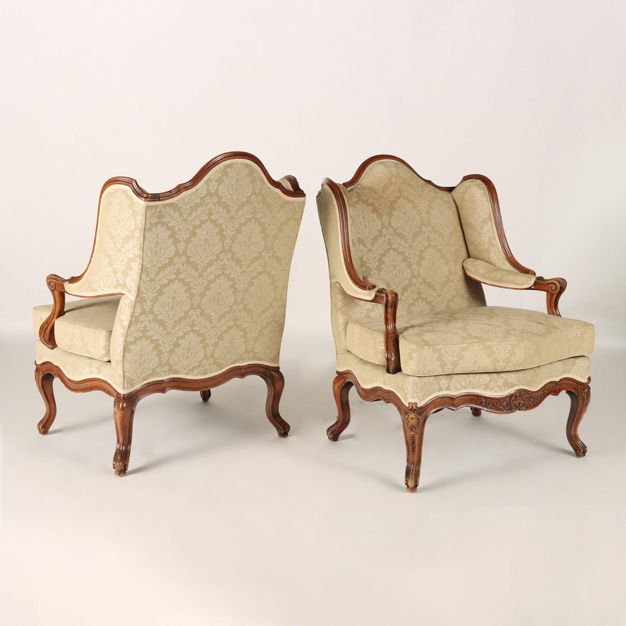 A pair of French Louis XV style carved Bergeres A oreilles, padded arms and cabriole legs, upholstered in beige colored damask. C 1900. Hard to find.