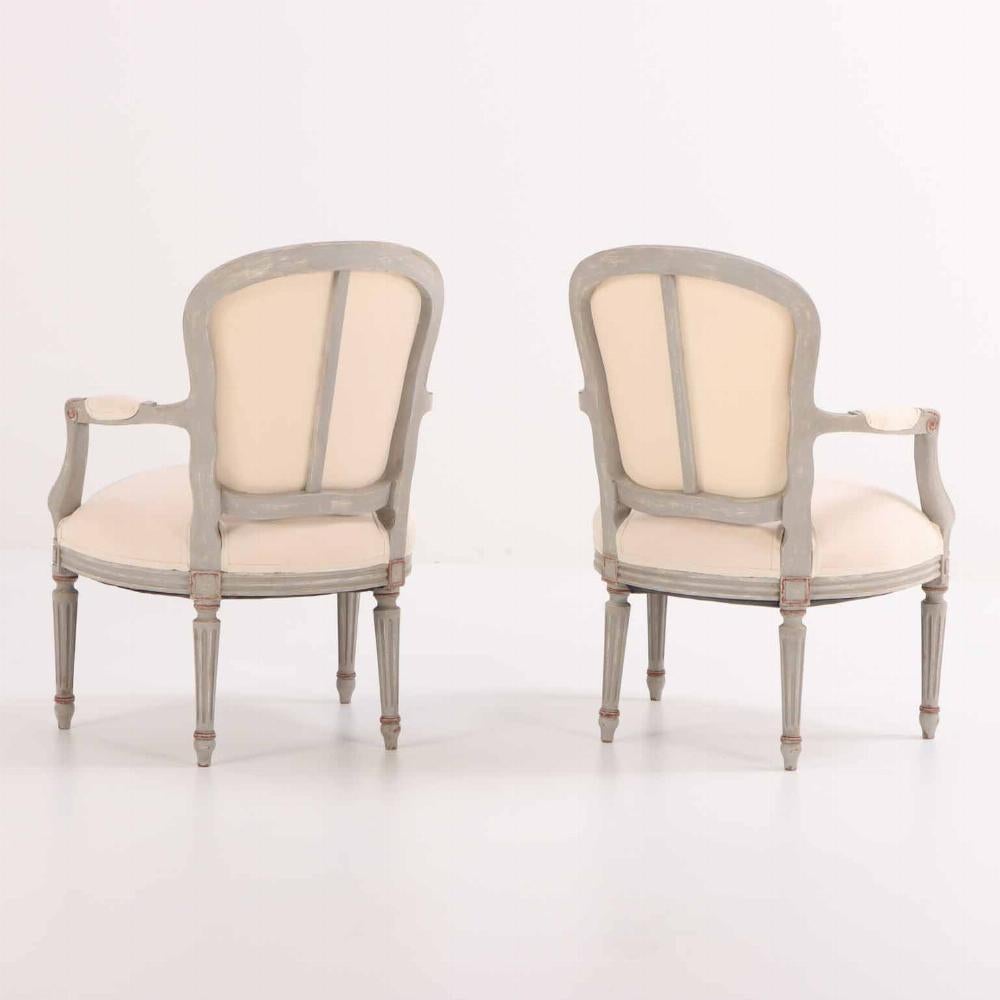 These comfortable grey painted and giltwood chairs envelop you with the arched crests and rounded backs, small padded arms and deep fluffy cushions all supported by round tapering and fluted legs. Recently reupholstered with new fabric and ready to