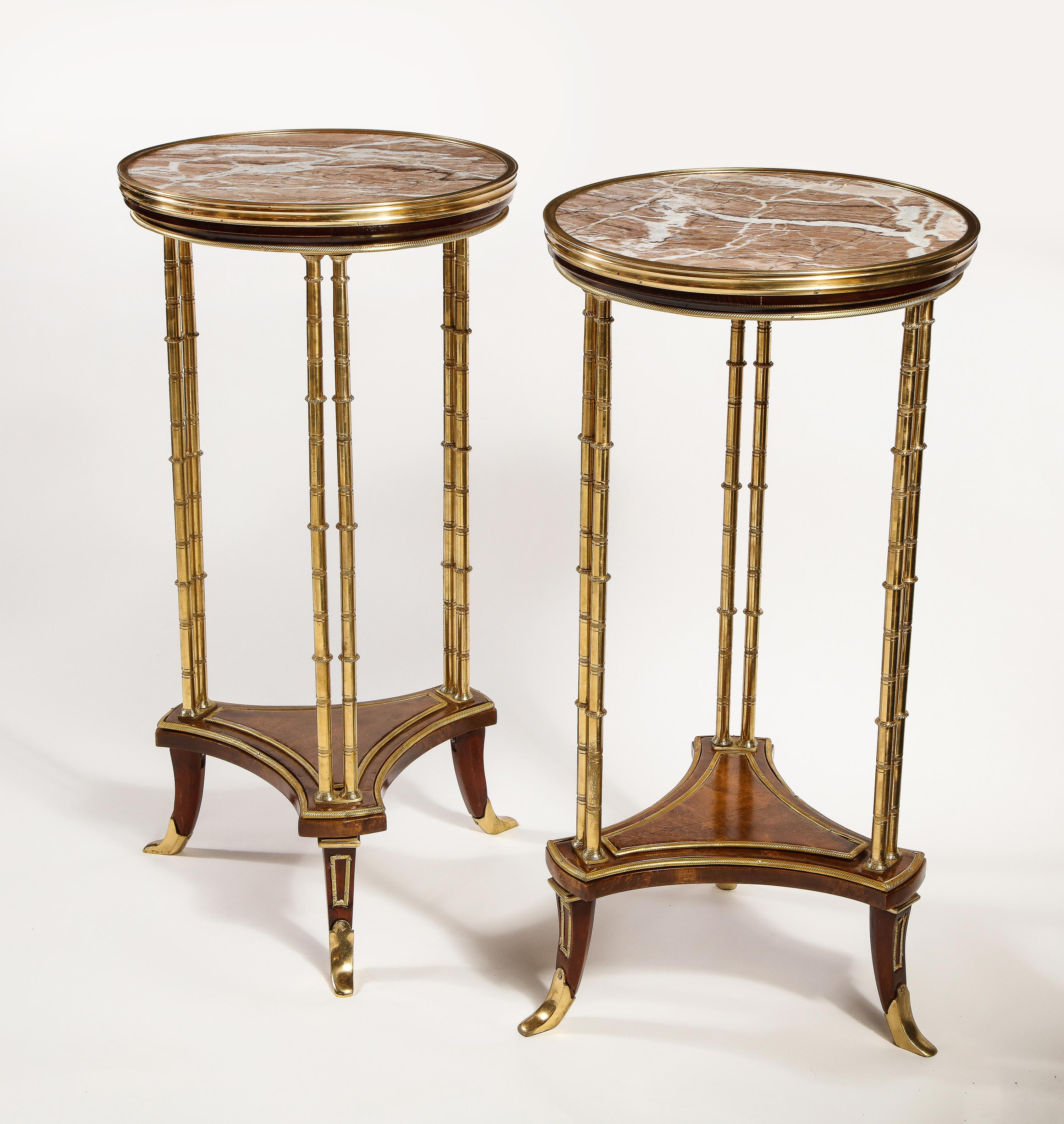 A pair of French Louis XVI style gilt bronze mounted mahogany marble-top circular form side tables of great workmanship embellished with gilt bronze bamboo legs, triangular center stretcher and further adorned with fine marble tops.