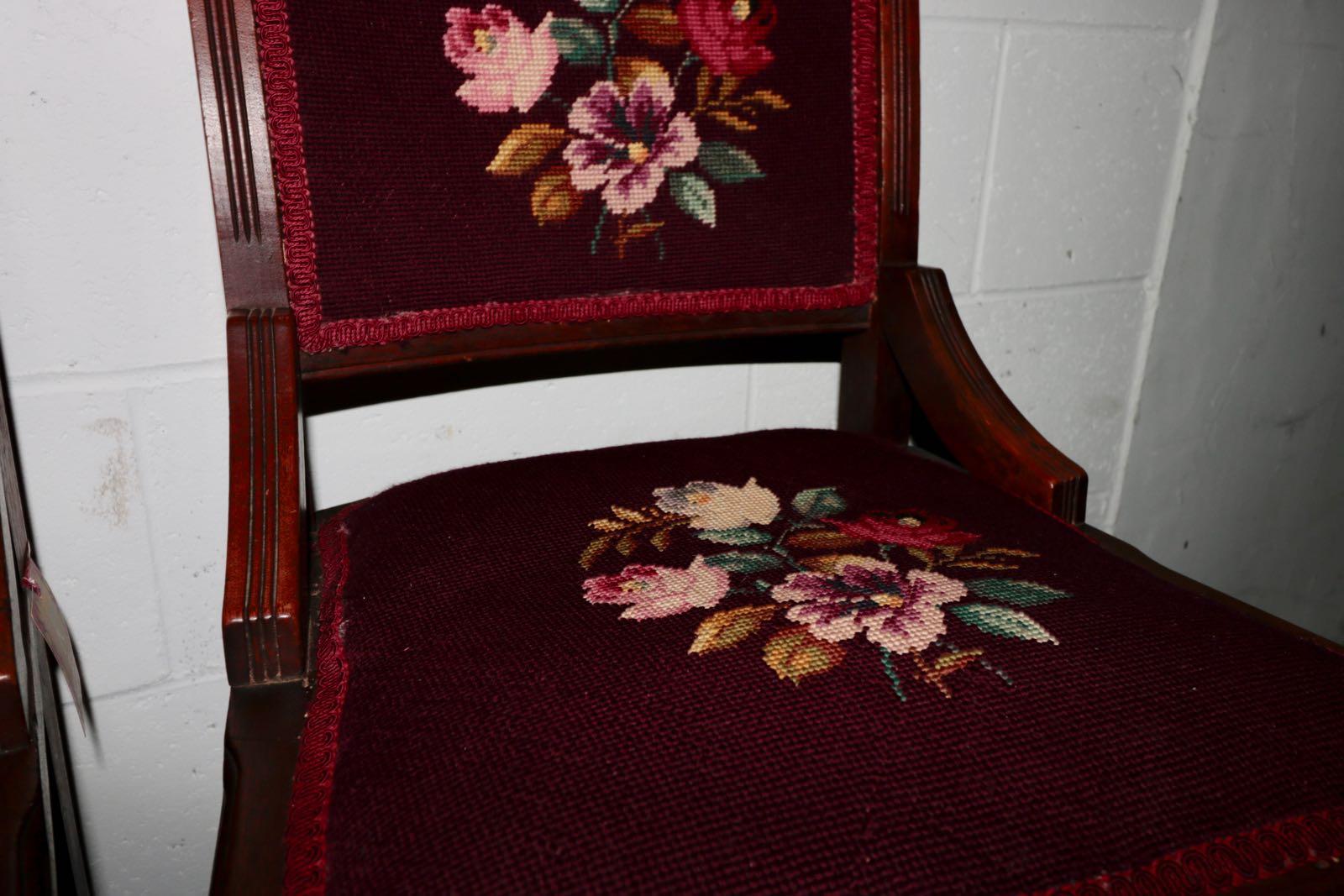 A pair of French mahogany hand carved scroll work crewel embroidered chairs. Elegant floral scroll work accent the top of each chair. Crewel embroidered wool fabric with fantastic colors adorn the seat and back. A pleasant flora. Of the Baroque