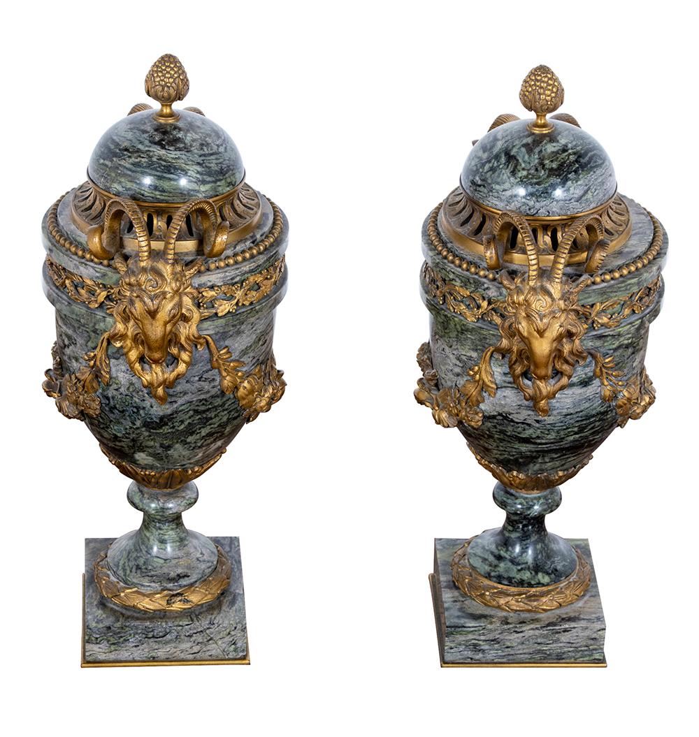 Presenting a magnificent pair of French Maurin green marble urns and covers exuding opulence and grandeur in the Louis XVI style, dating from the late 19th to early 20th century.

Each urn is meticulously adorned with ornate ormolu mounts featuring