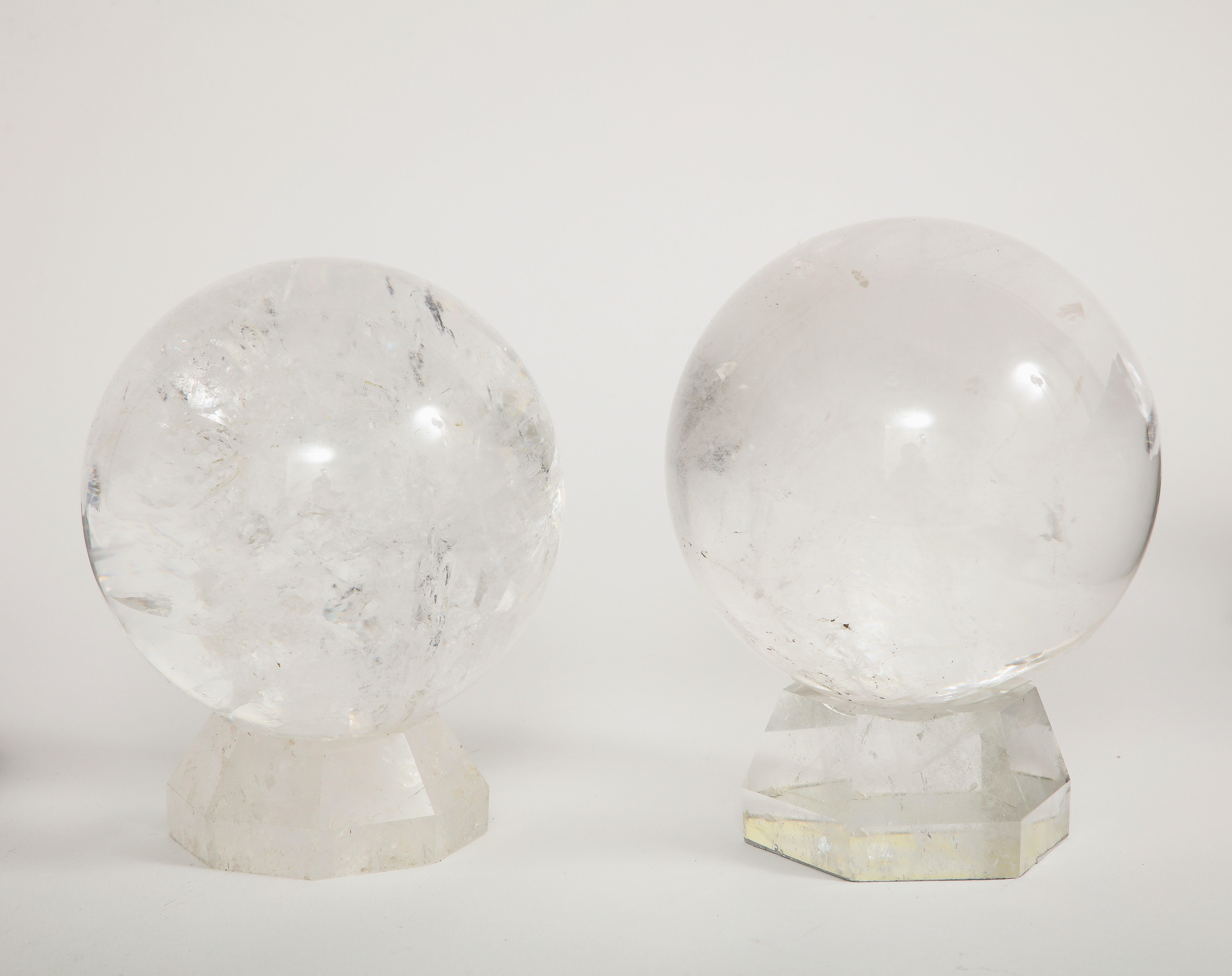 A Pair of French Mid-Century Modern rock crystal hand-craved and hand-polished orbs/spheres on original rock crystal stands. Each orb is hand carved and hand-polished from a single piece of very clear natural rock crystal. The orbs rest on two