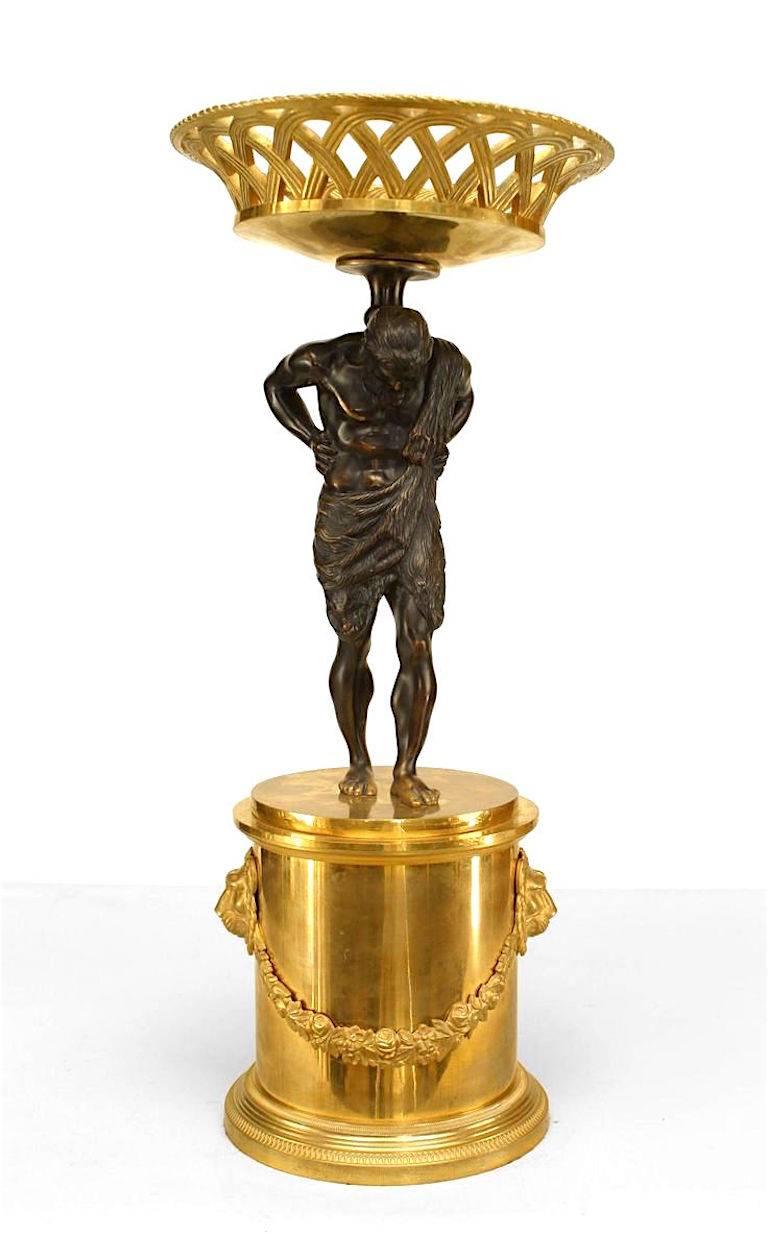 Paire de tazzas/centres de table en bronze de style néoclassique français (milieu du XIXe siècle) avec une figure d'Atlas soutenant un panier tressé doré. Il repose sur une plinthe ornée de guirlandes et de têtes de lion.
