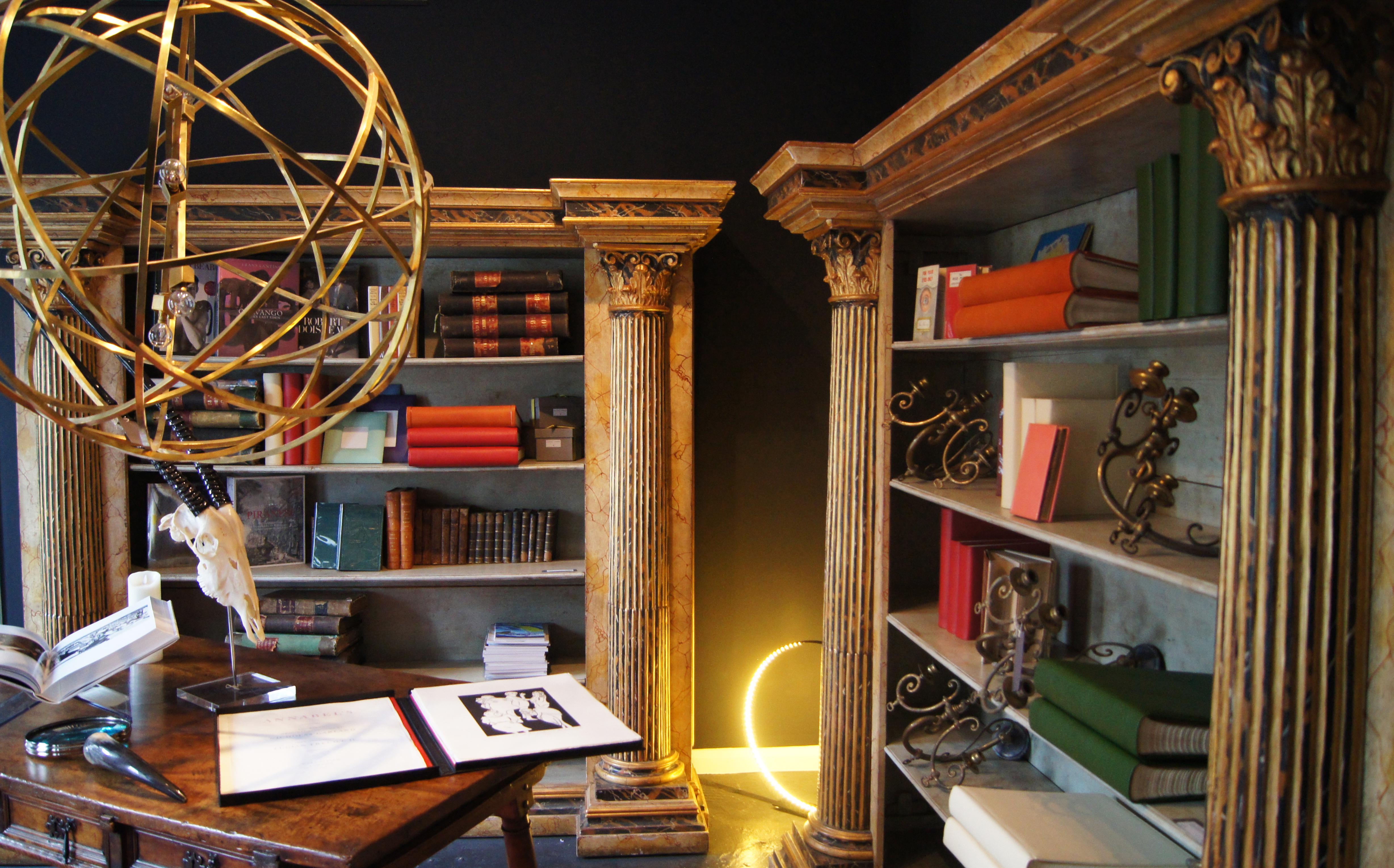 A pair of large neoclassical style gilt and painted pine open bookcases, early 20th century, circa 1900-1910, simulated Portor and Siena marble decor, each with a moulded cornice above five shelves flanked by projecting stop-fluted Corinthian