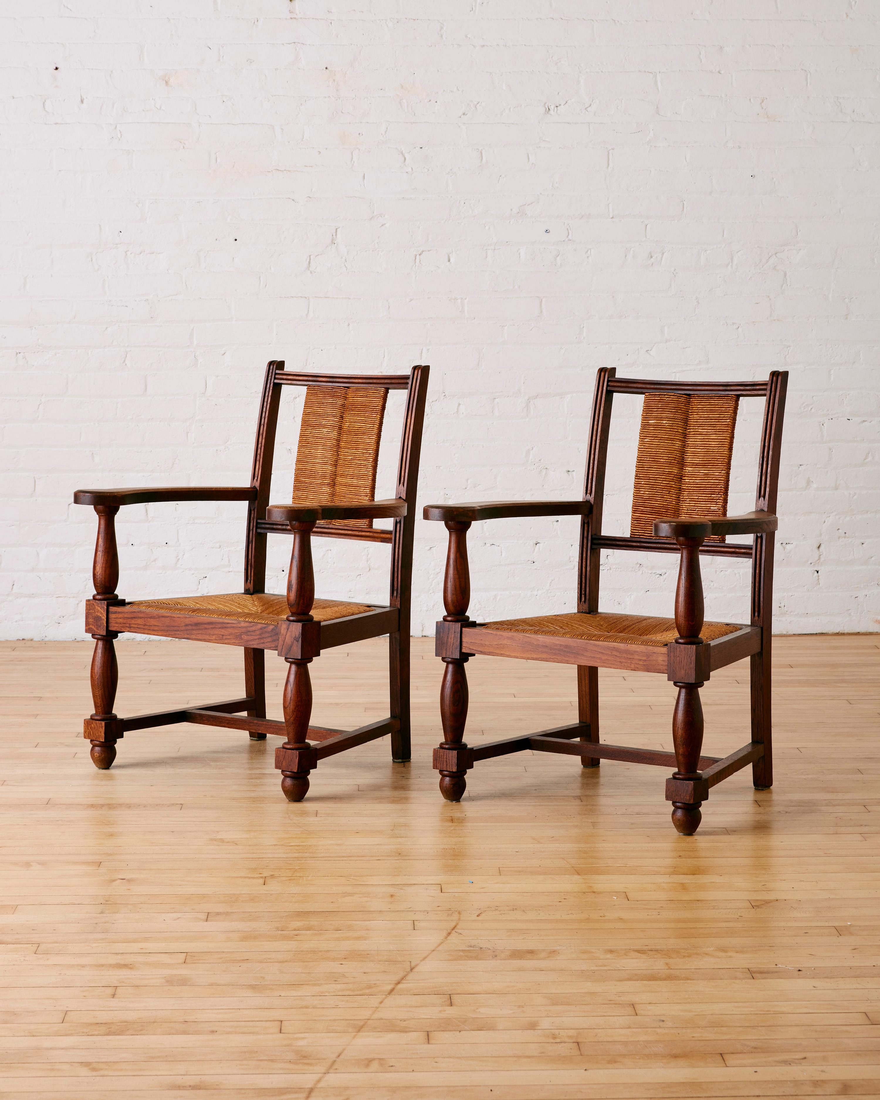 A Pair of French Oak Arm Chairs in The Manner of Charles Dudouyt featuring rush seating and backrest. 