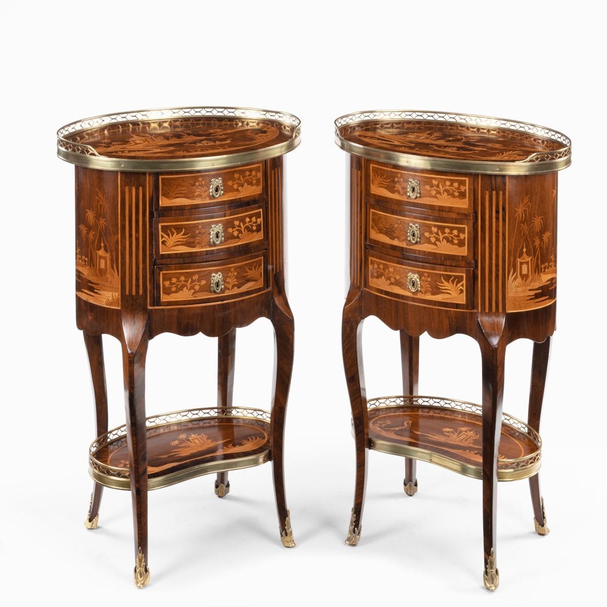 A pair of French rosewood occasional tables, each of oval form with three small drawers set upon cabriole legs joined by a kidney-shaped shelf, decorated in boxwood and kingwood marquetry with oriental landscapes showing a courtly boat on a lake