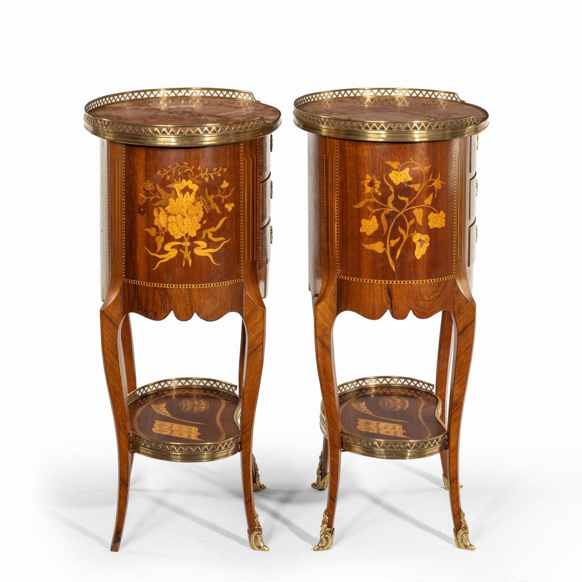 A pair of French rosewood oval marquetry bedside tables with marble tops, each of oval form with three small drawers set upon cabriole legs joined by a kidney-shaped shelf, decorated in boxwood and kingwood marquetry with oriental landscapes showing