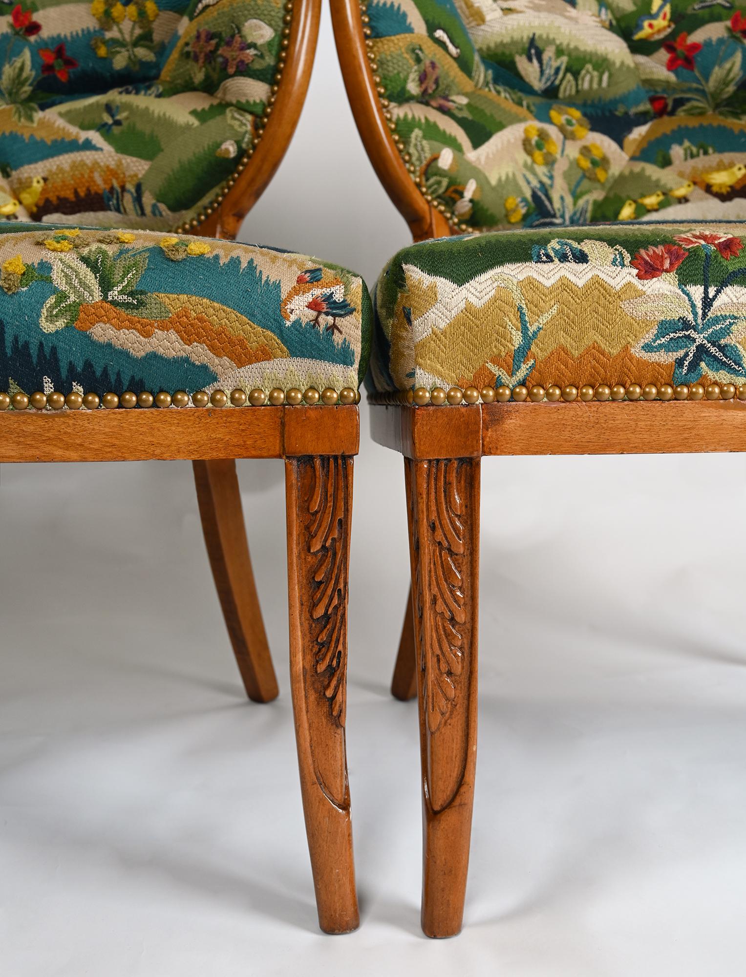 A pair of right and left facing French open armchairs with splayed tapered legs having hand carved acanthus leaf detail. Each leaf form curved asymmetrical back with upholstery in sections surrounded by rounded walnut frames with new hand
