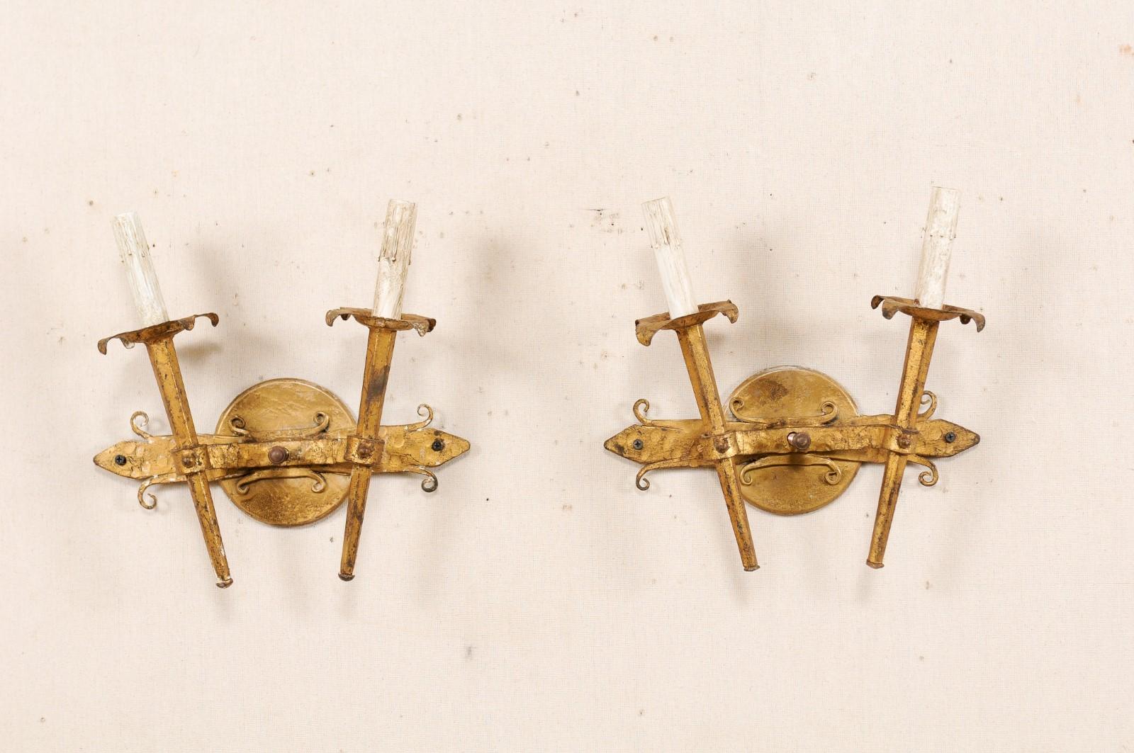 Coppia di applique francesi a due luci in ferro della metà del XX secolo. Queste appliques vintage forgiate a mano, provenienti dalla Francia, sono dotate di due luci a forma di torcia montate in modo da essere inclinate verso l'esterno e fissate