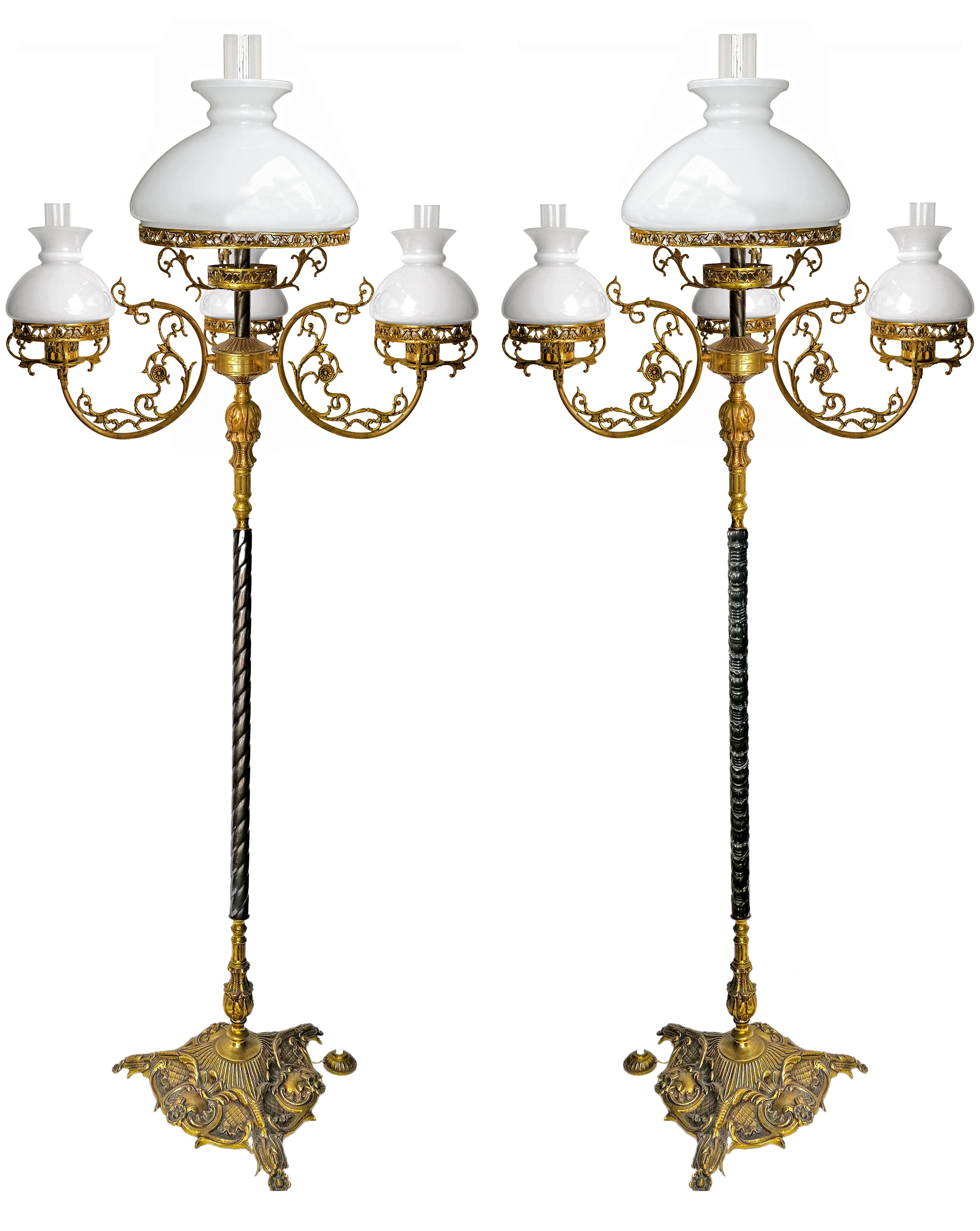 Magnificent pair of floor lamps in cast and chiseled gilt bronze and patinated brass. Gorgeous base with very pretty bronze features. It is cast in a triangular molded shape with three claw feet. Brass rods with different patterns. 
Opaline glass