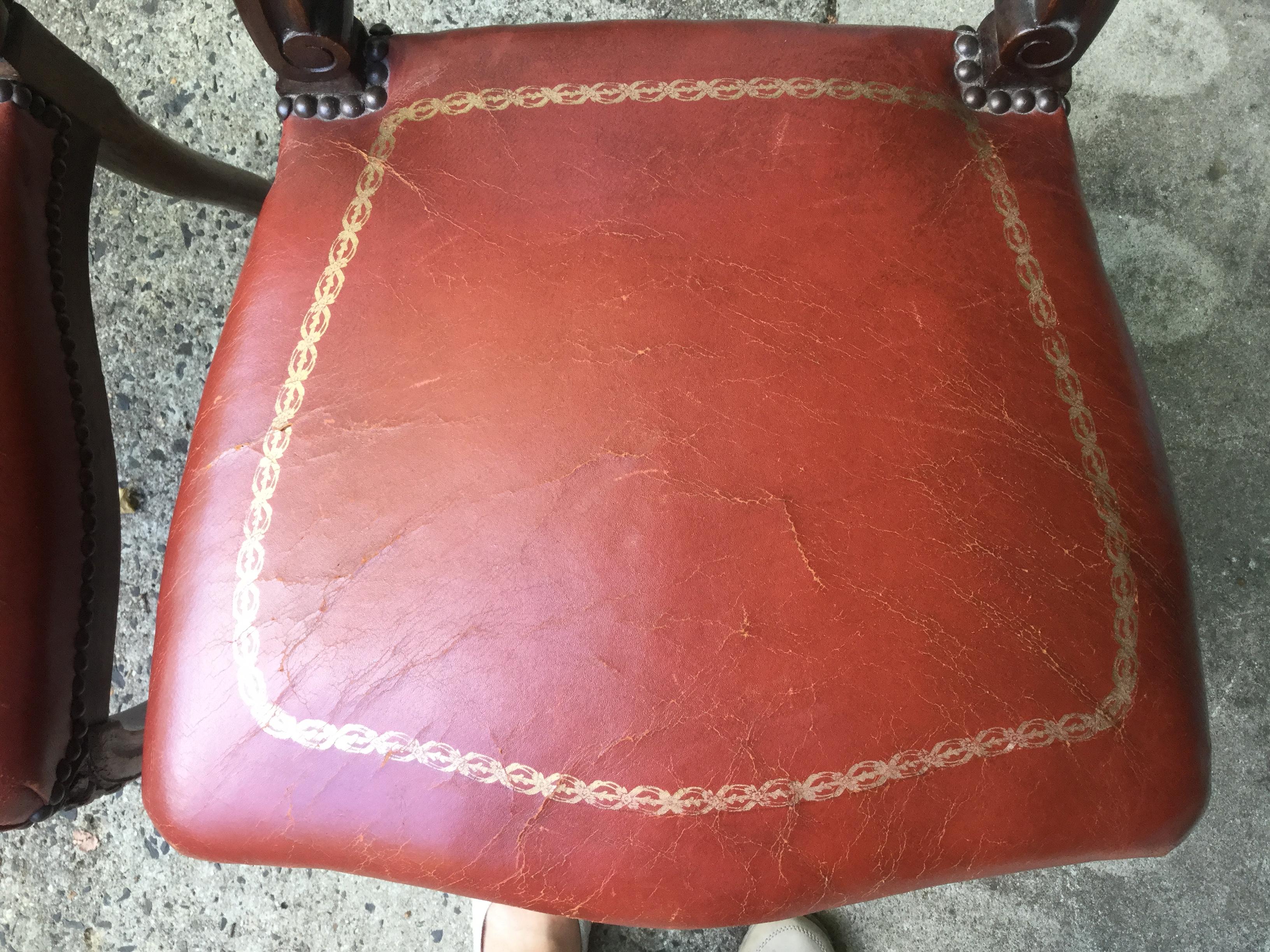 Charming pair of French Louis XV-style leather boudoir chairs. Made of walnut, these chairs feature a delicately carved frame and red leather seats with embossed gold accents. Dating to the 1920s, the leather is original and in very good condition.