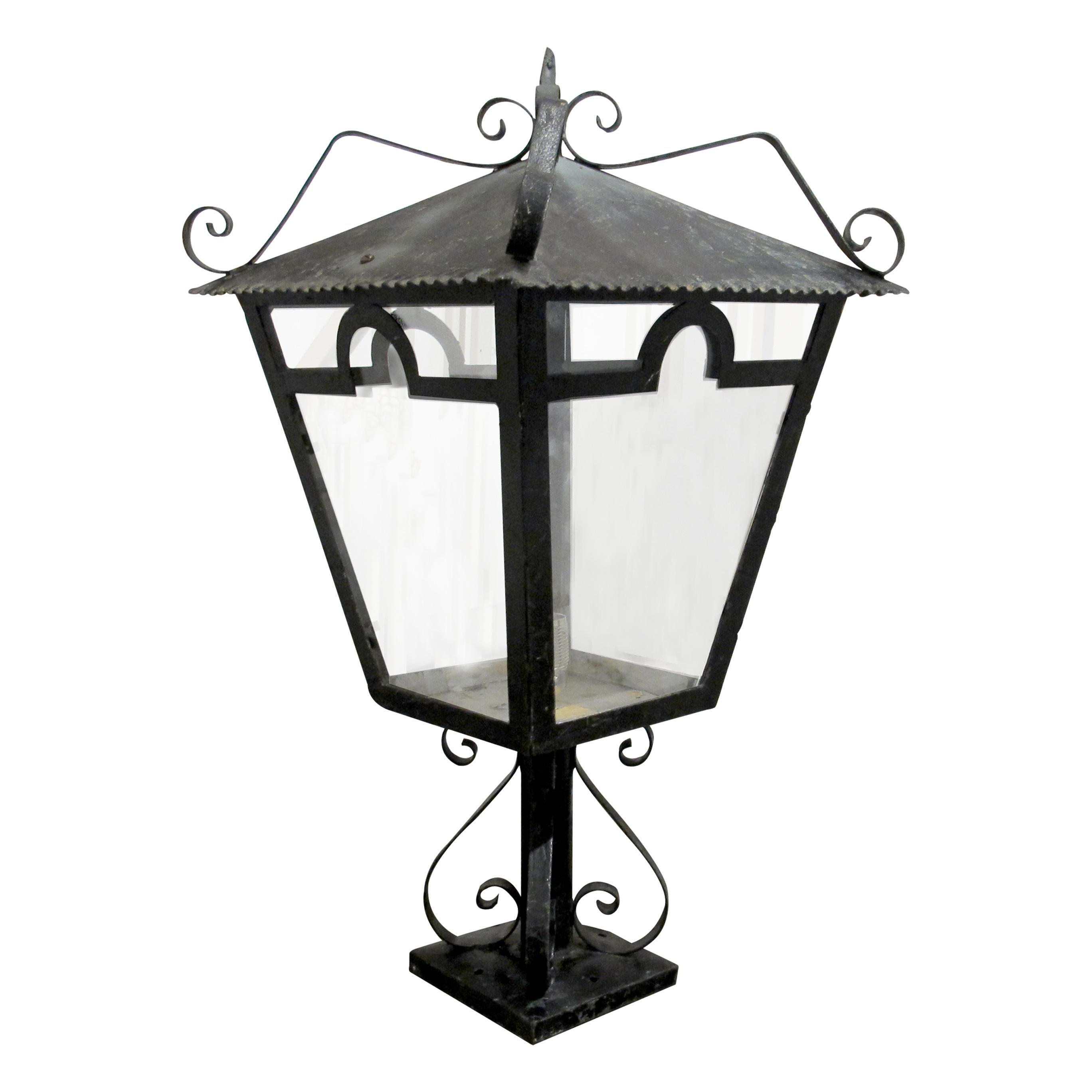 Paire de lanternes piliers décoratives en fer forgé françaises du milieu du 20e siècle, chacune de forme carrée effilée avec des panneaux en verre transparent placés dans des cadres arqués, surmontés d'un toit à forte pente bordé d'un rebord