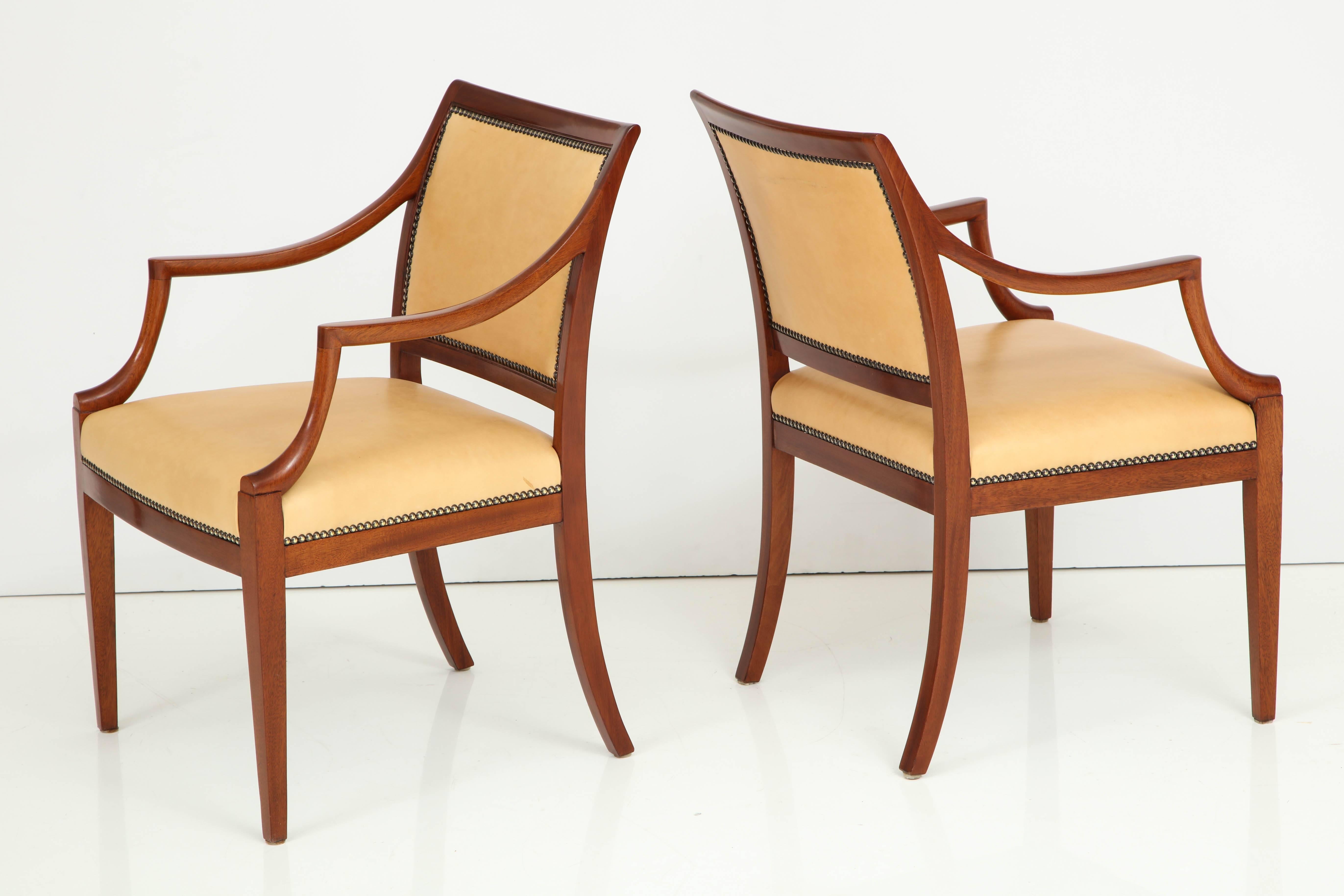 A pair of Danish mahogany open armchairs by Frits Henningsen with leather seat and back finished with French nailheads, circa 1940s, a rich mahogany frame with downswept armrests raised on square tapered legs. New leather upholstery.