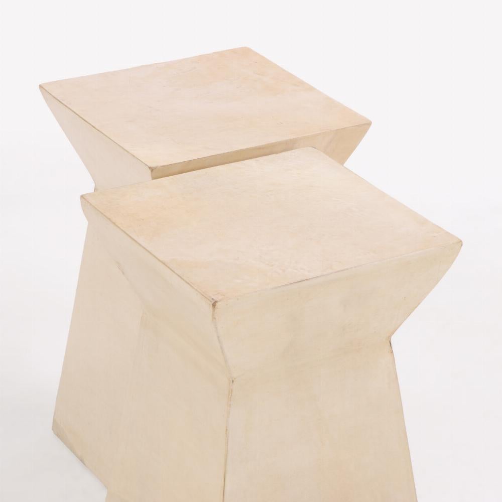 Une paire de tables à boissons contemporaines raffinées, chacune revêtue de parchemin naturel avec des variations de tons doux et une finition subtilement lustrée. De forme minimaliste mais riche en textures, les lignes épurées et l'échelle compacte