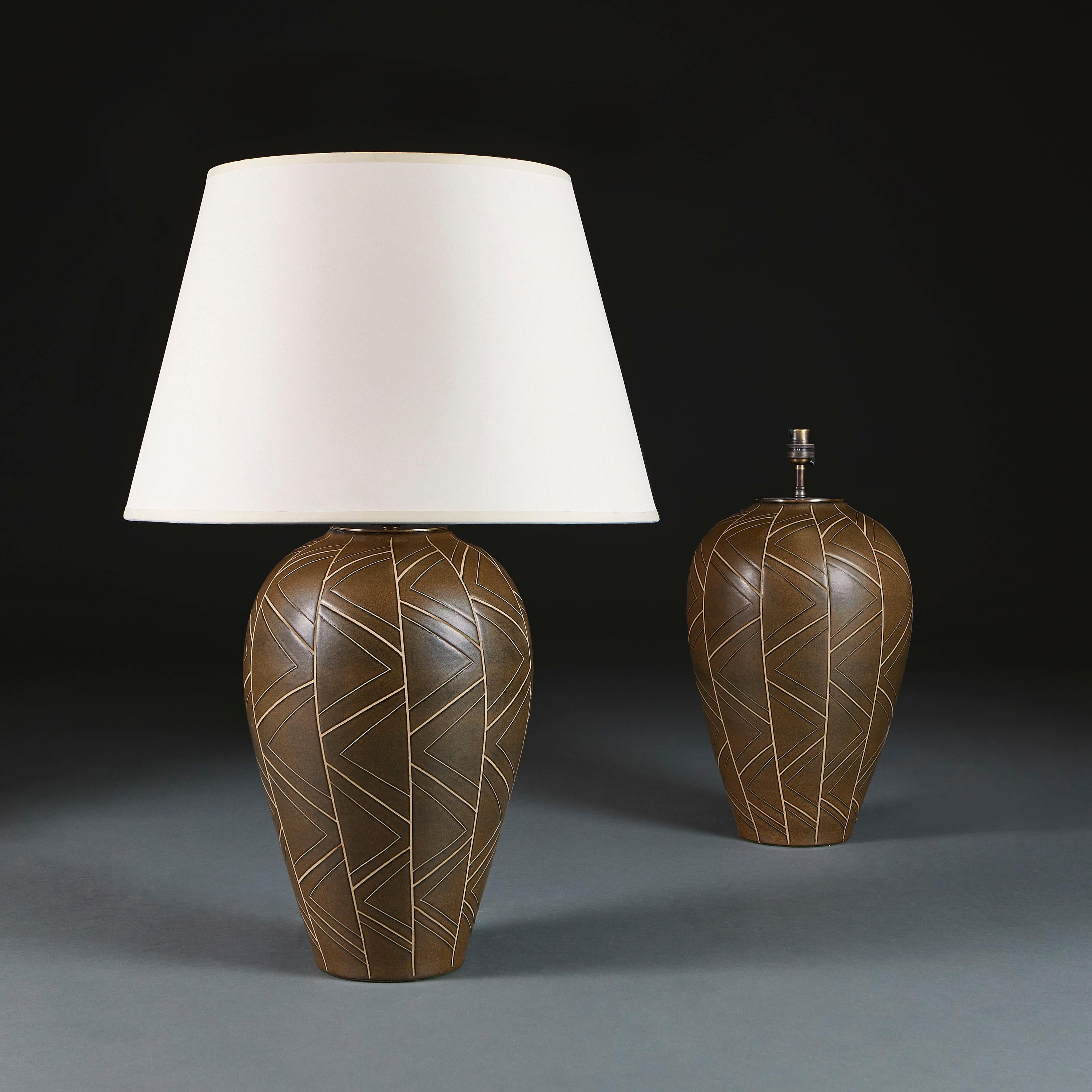 England, circa 1940

A pair of mid century art pottery lamps of large scale, with geometric scraffito motives to the bronze glaze.

Height 38.00cm
Height with shade 69.00cm
Diameter of base 12.00cm.

Please note: This is currently wired for the UK