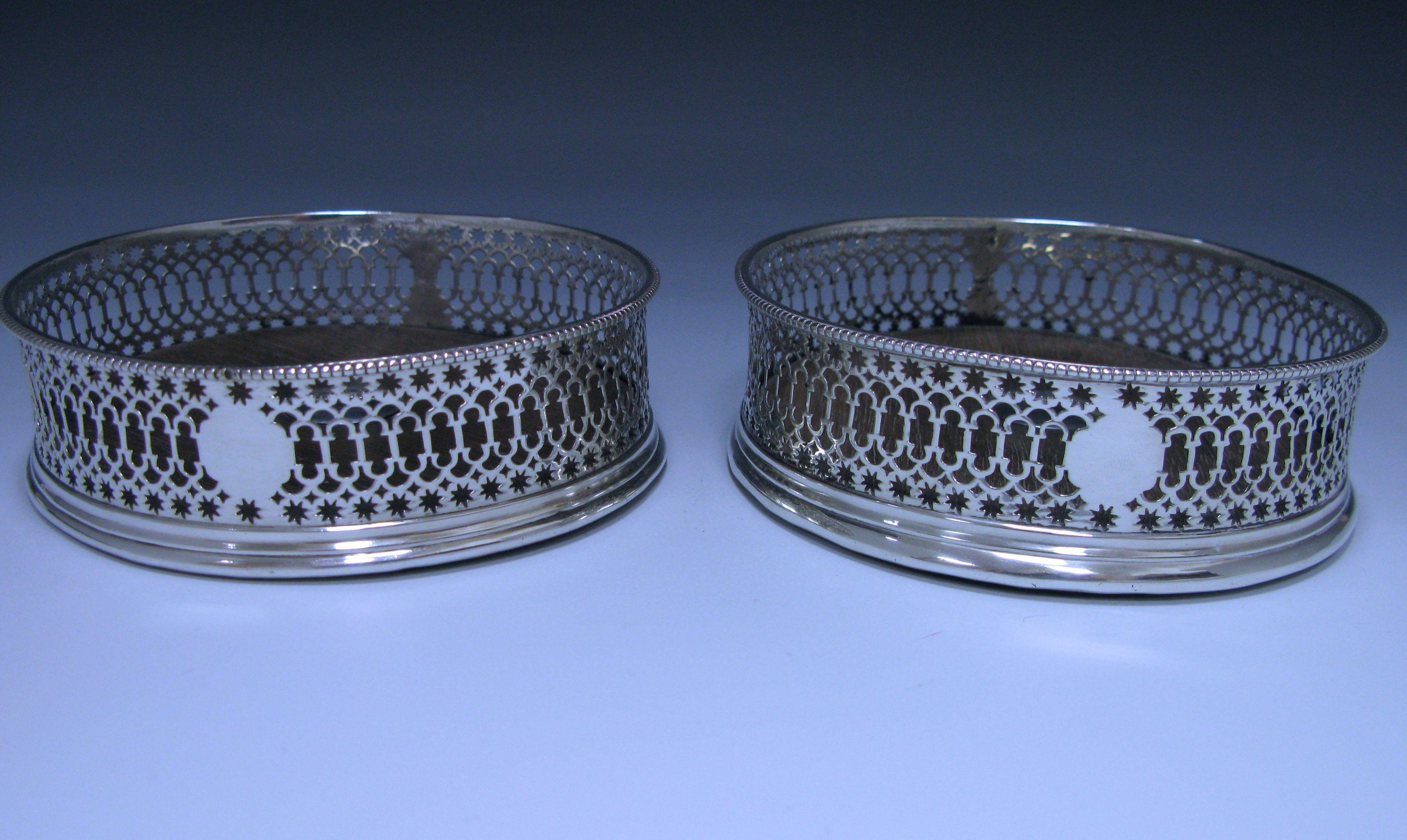A pair of delightful George III antique sterling silver coasters with beaded rims, star and arcade piercing and the wooden bases have a central silver button. The pierced borders also contain a vacant cartouche and panel containing the hallmarks.