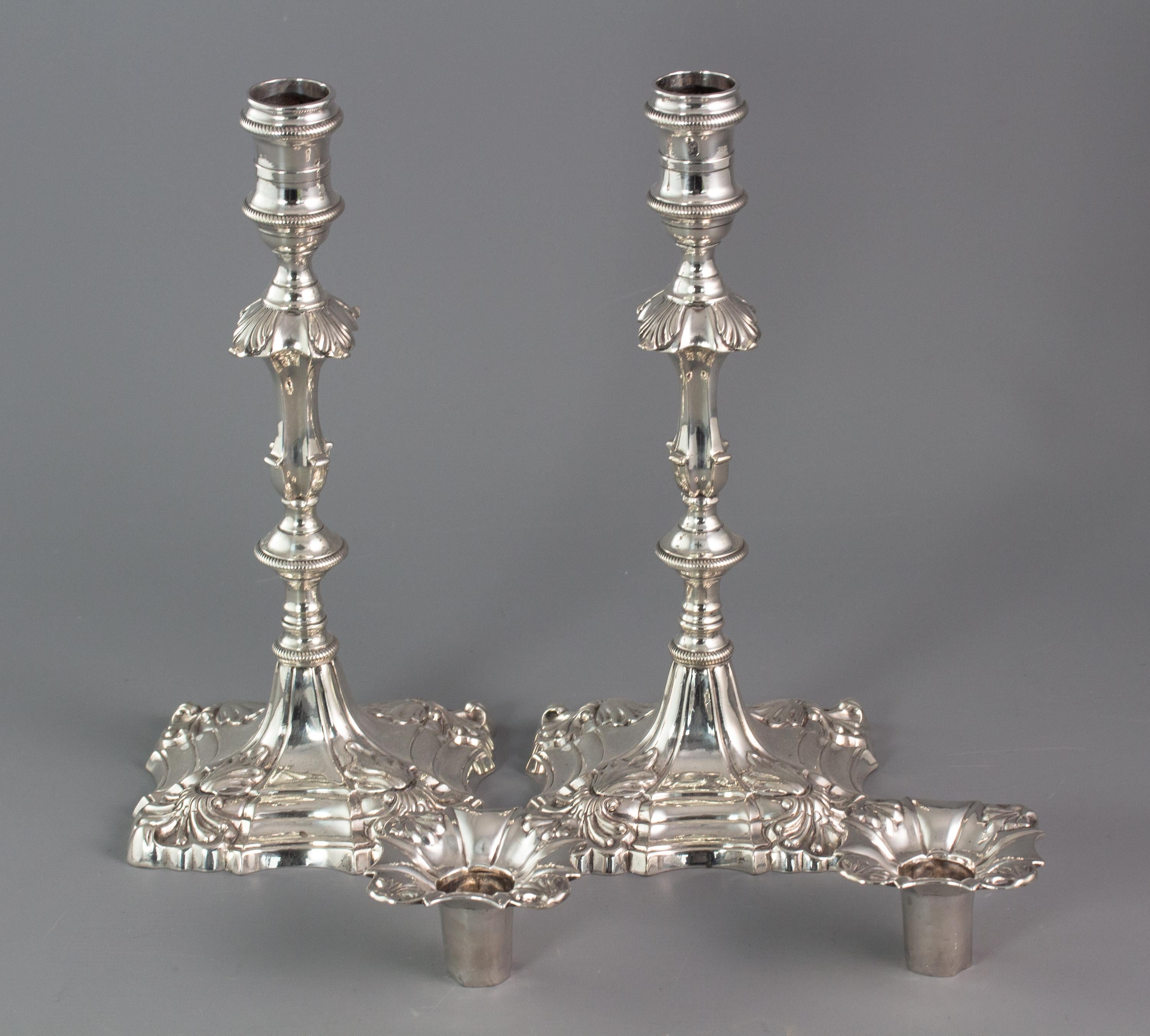 A superb pair of cast George III silver candlesticks by Ebenezer Coker London 1764. With square bases shaped and stepped with flame and shell form corners. The fluted columns rising above a rope decorated circular knop to a square knop with matching