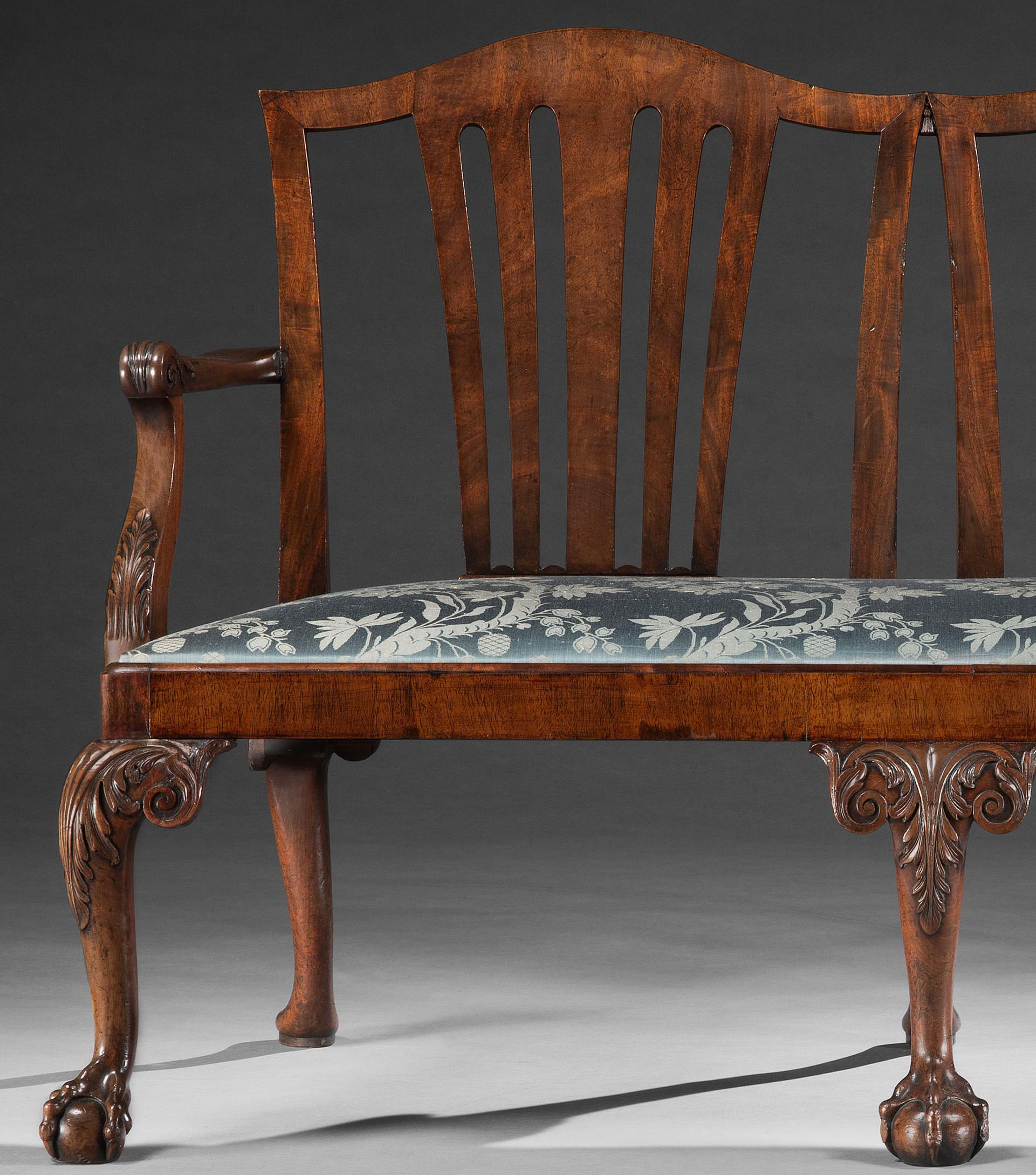 A Fine Pair of George II Mahogany Chair Back Settees
With curved top rails above a tapering vertical splat, joined by carved tassels, the scroll shaped arms with acanthus carving, above rectangular drop in seats, resting on well shaped bold acanthus