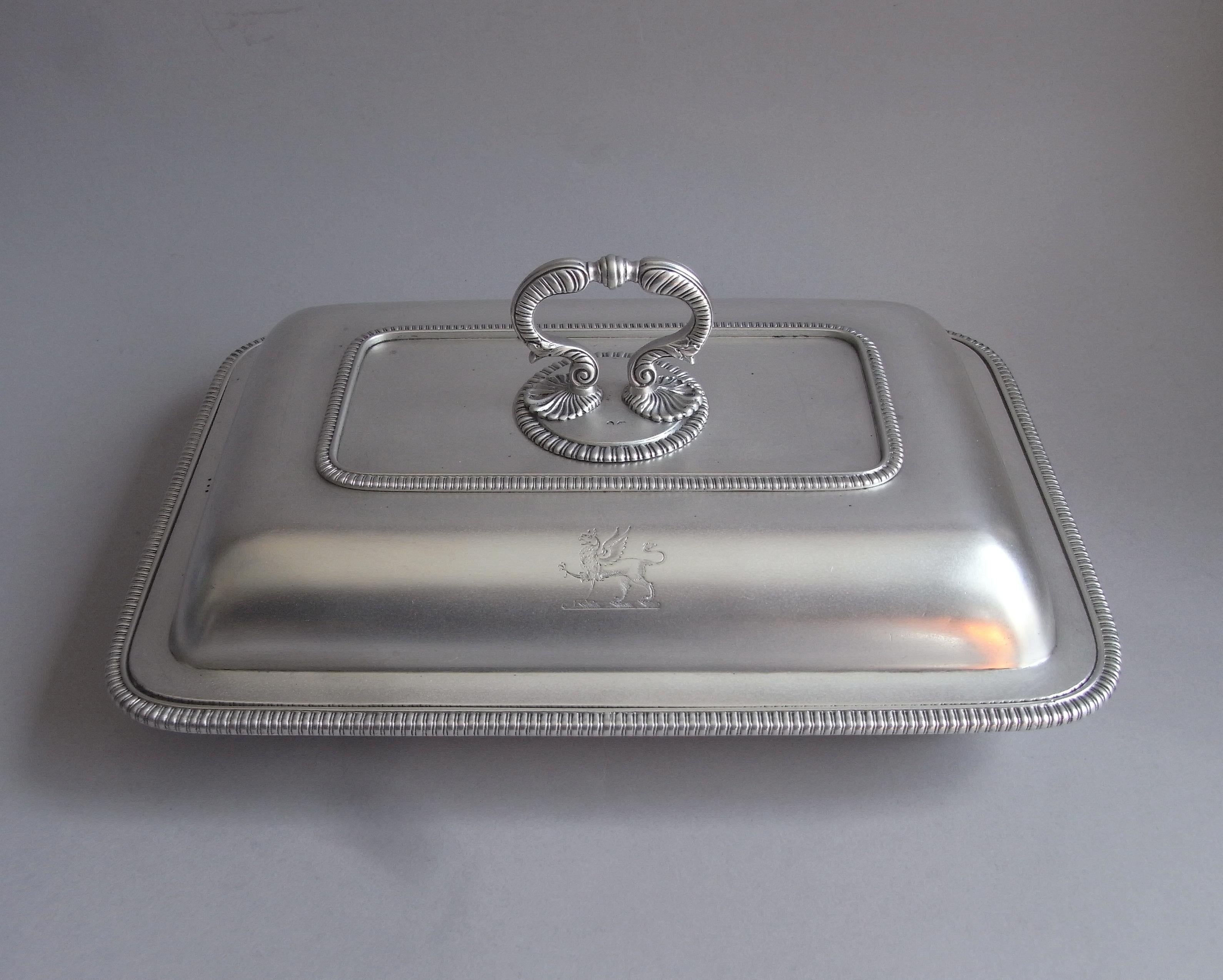 This exceptional pair of George III antique sterling silver entree dishes were made in London in 1800 by Richard Cooke. The Dishes are rectangular in form, with lobed borders, and terminate in a most unusual double scroll handle mounted on two