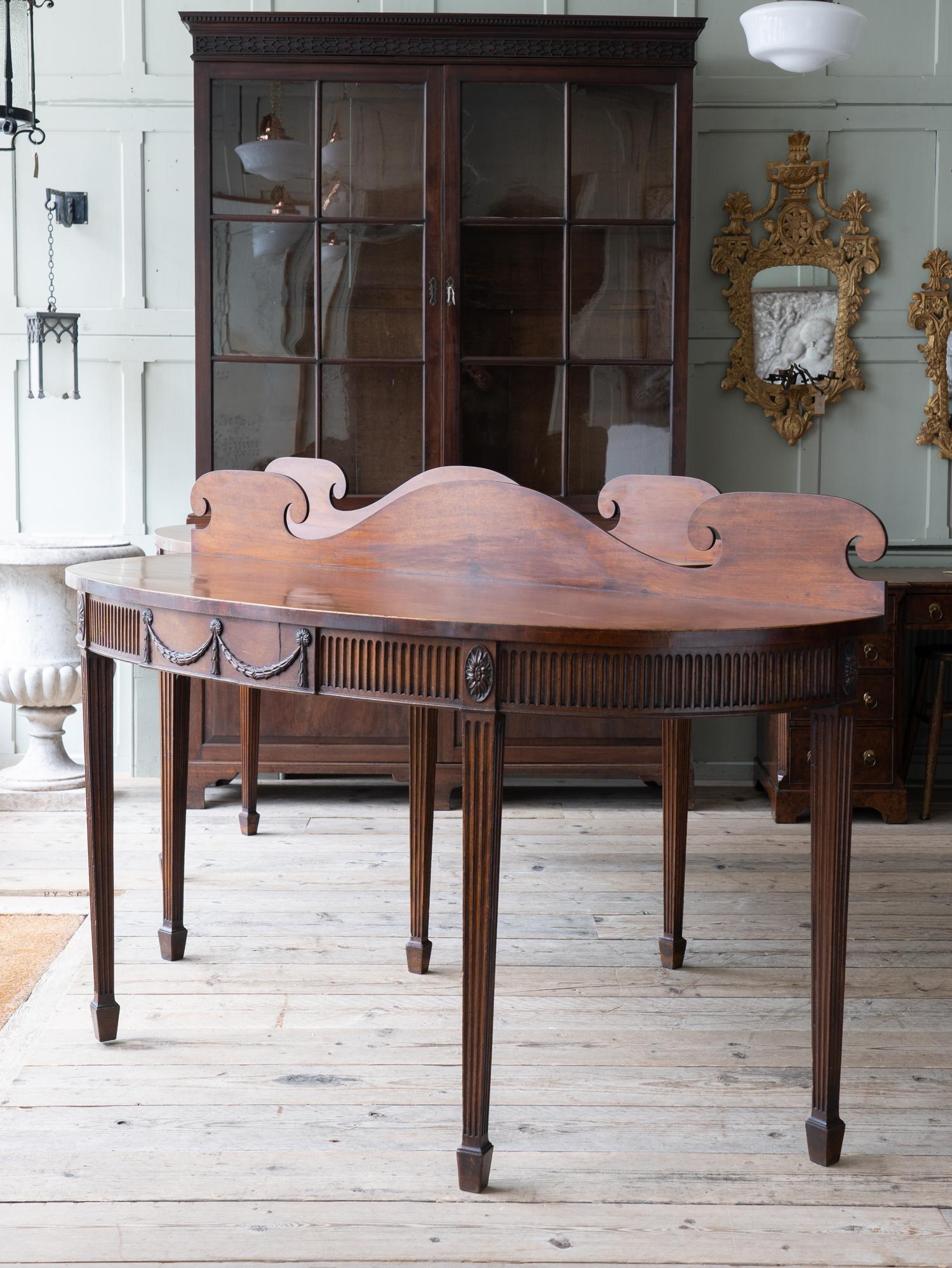 A pair of large mahogany console-serving tables.

The galleried mahogany tops above a fluted frieze with oval paterae, central tablet with roundels and swags on square tapering and fluted legs with spade feet.

Exceptional scale, colour and