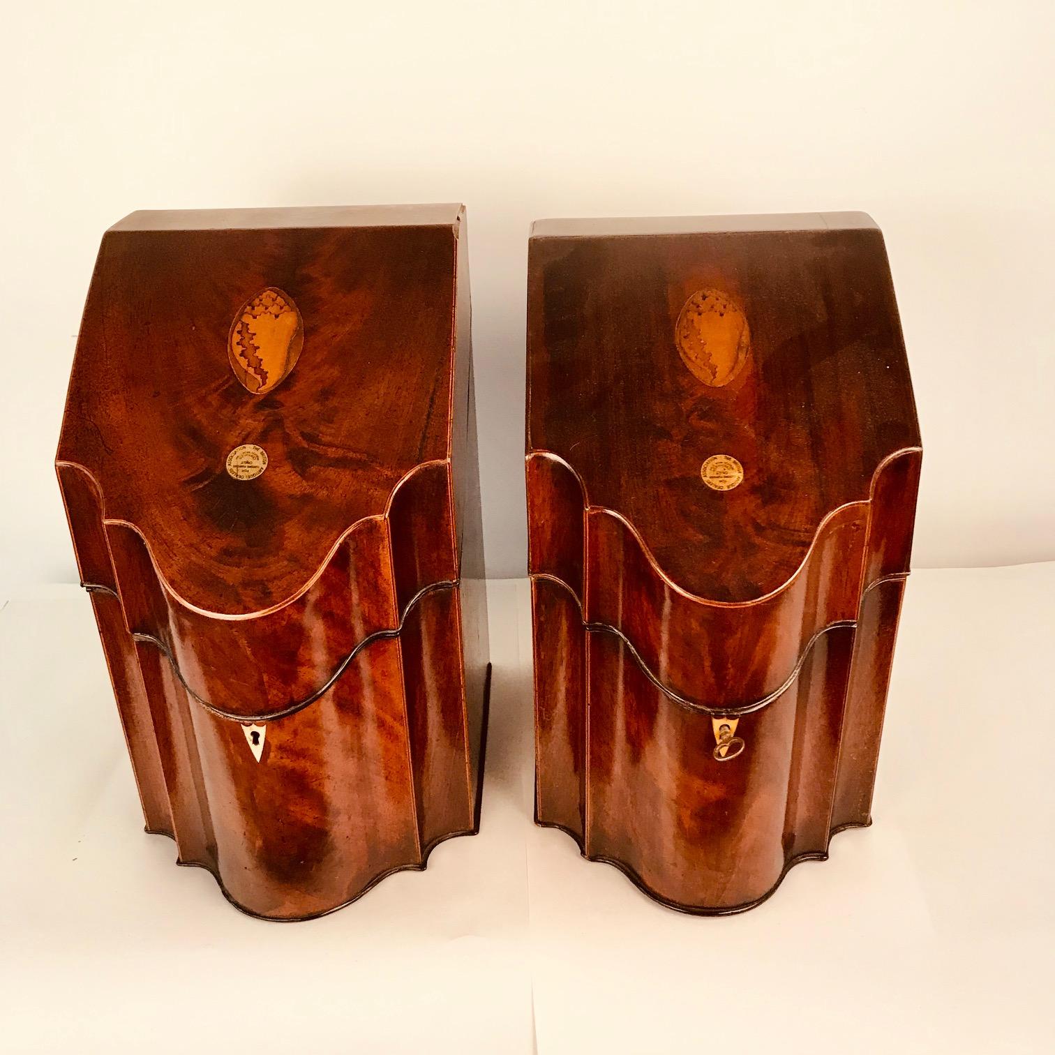 This pair have the typical shape of boxes from this period, with shaped serpentine front, sloped hinged lid, and boxwood and ebony lines. Each cover is inlaid with an oval patera and inside with a compass rose. They retain their original pierced,