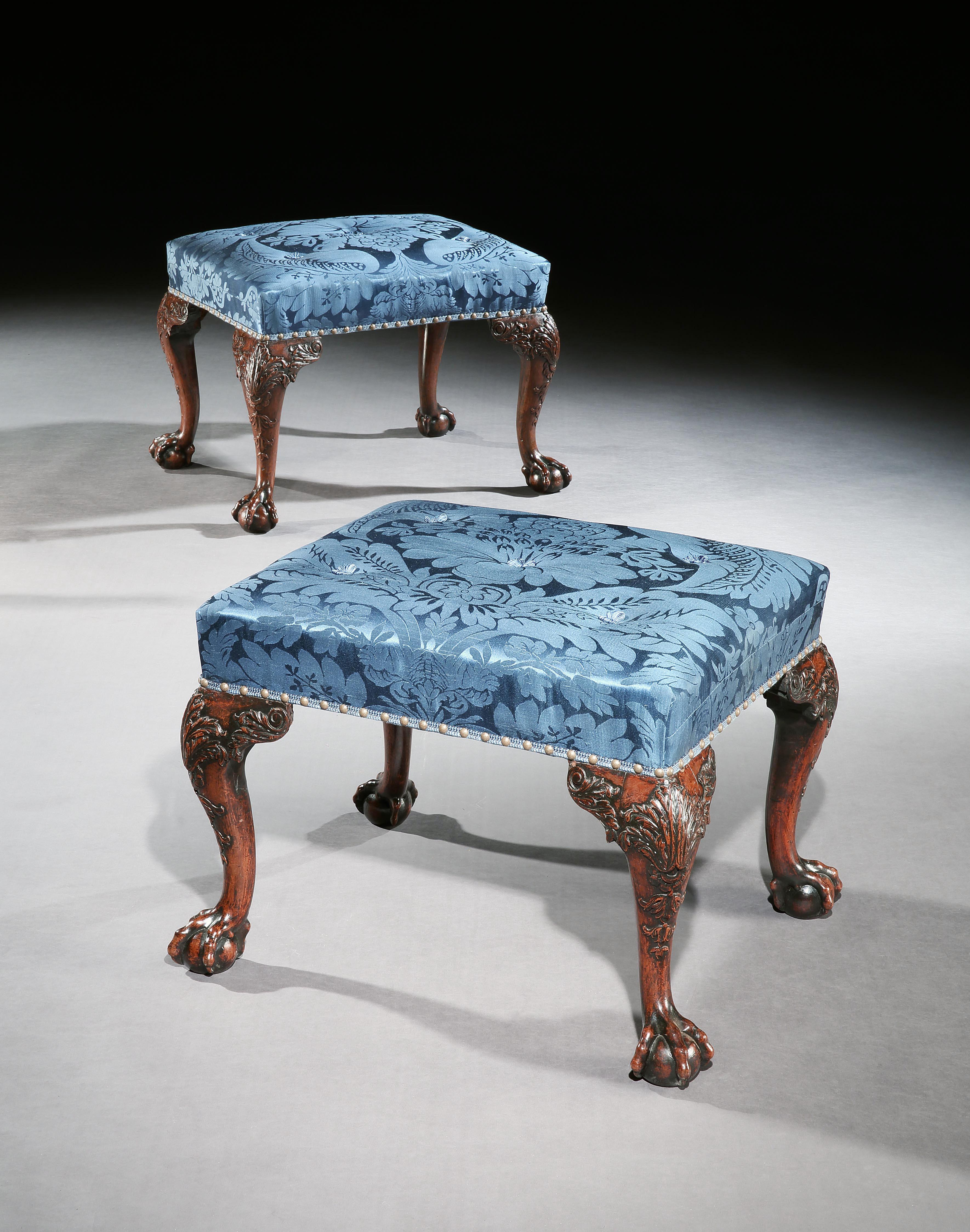 A pair of George III mahogany stools well carved with acanthus leaves and scrolls. Terminating in ball and claw feet, covered in a blue silk damask.

English, circa 1770.

This fabulous pair of stools remain in wonderful untouched condition.